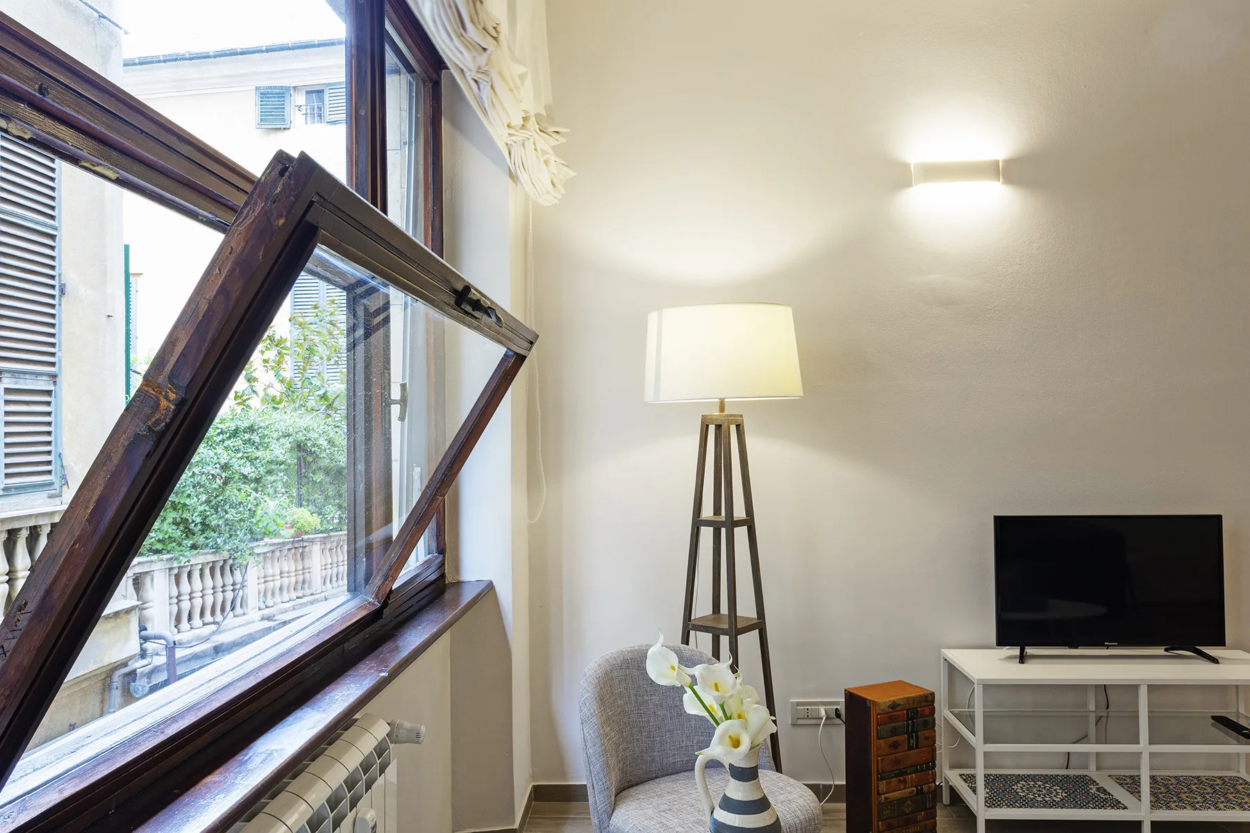 A bright living room with an open window, seating, and a television.