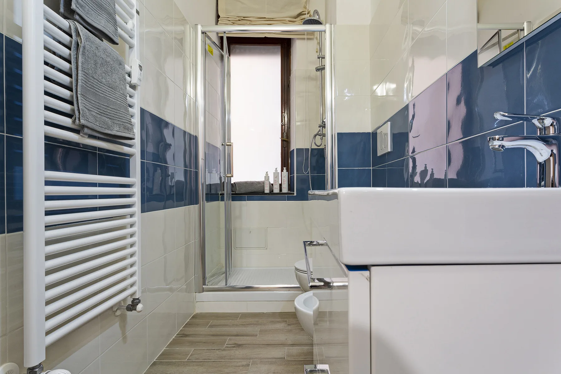 A tiled bathroom with a bathtub, shower, and towel radiator.