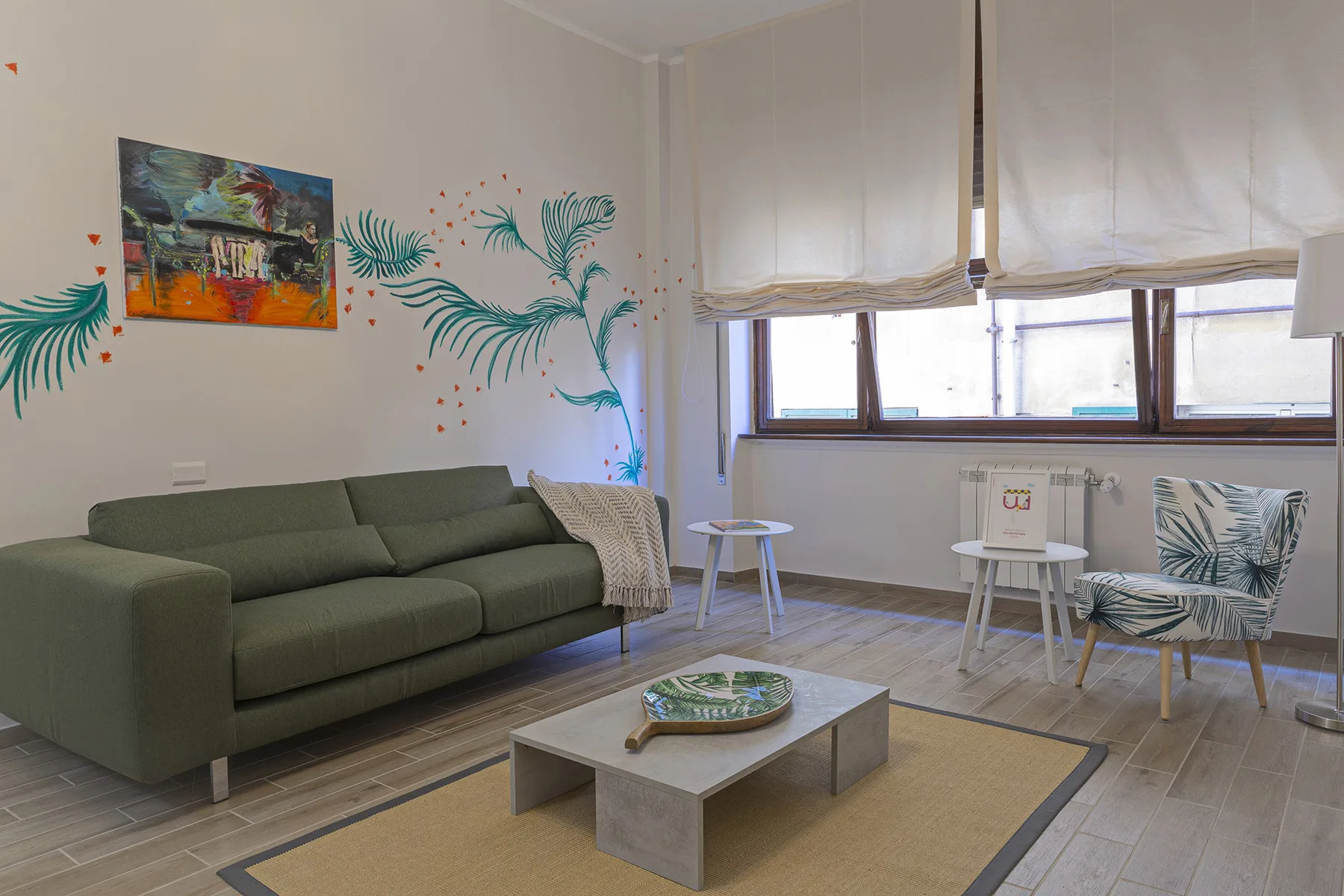 A living room with a green sofa, a coffee table, and colorful wall art.