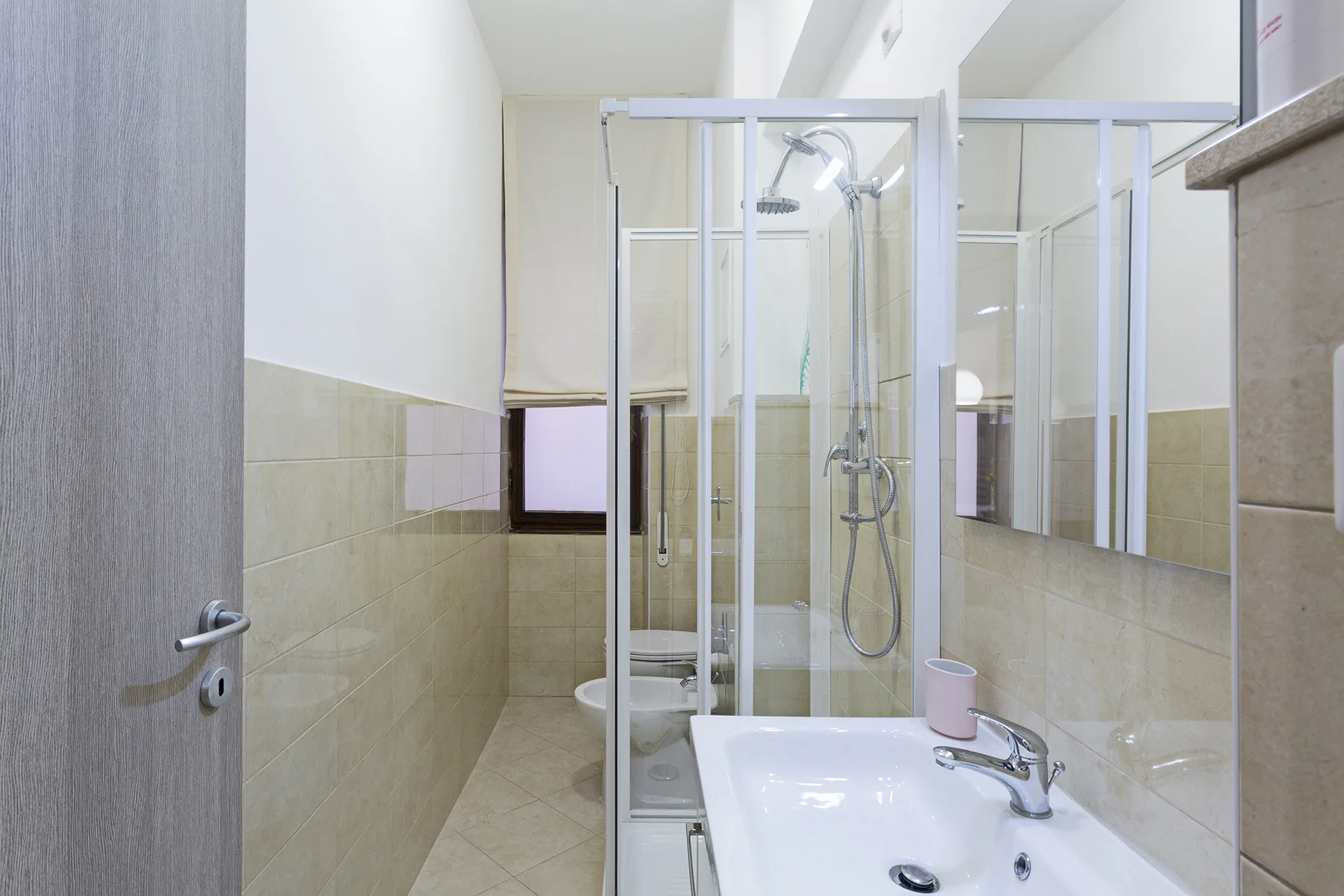 A tiled bathroom with a glass shower and a sink.