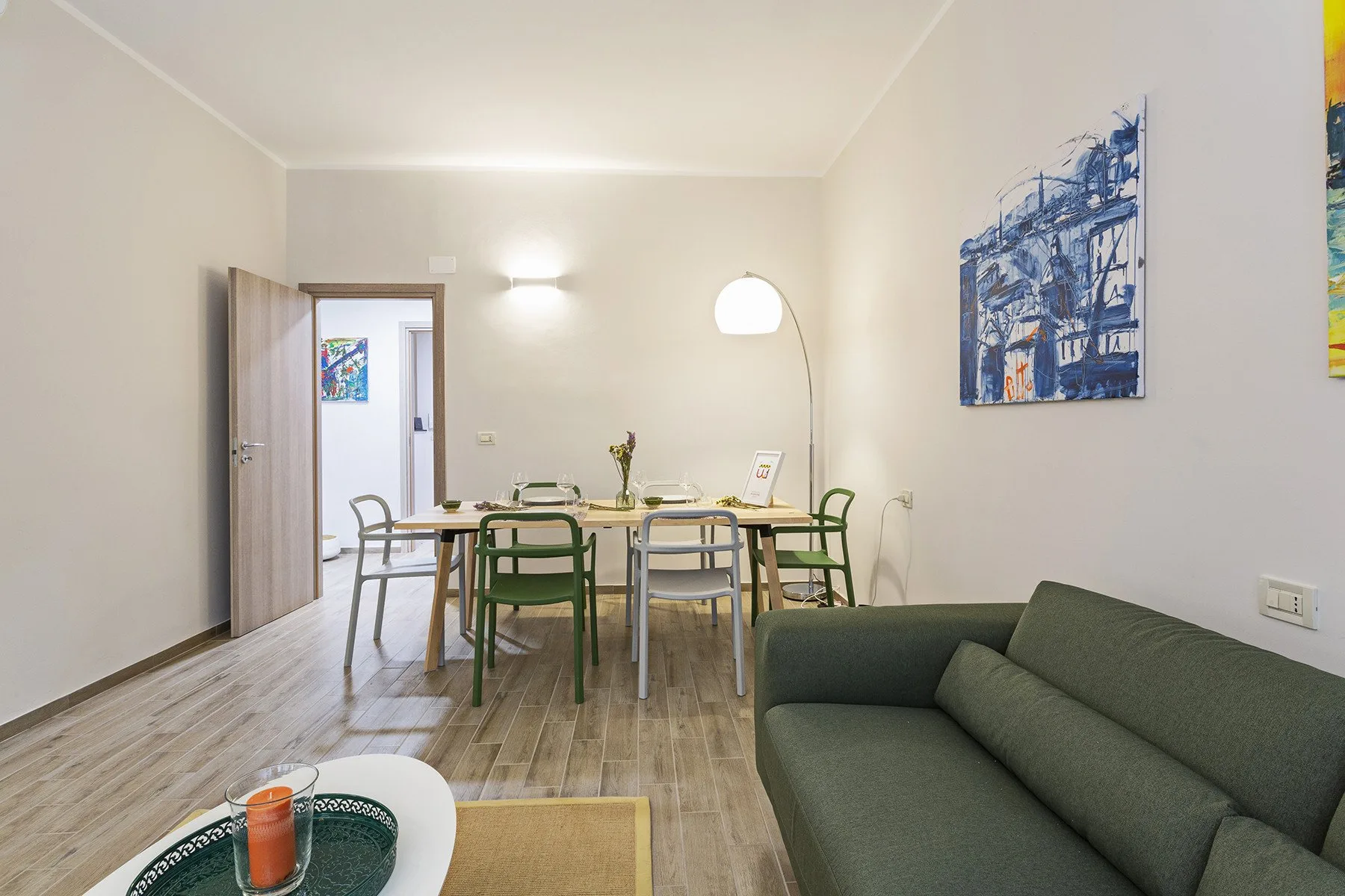 A dining and living area with a table, chairs, and a green sofa.