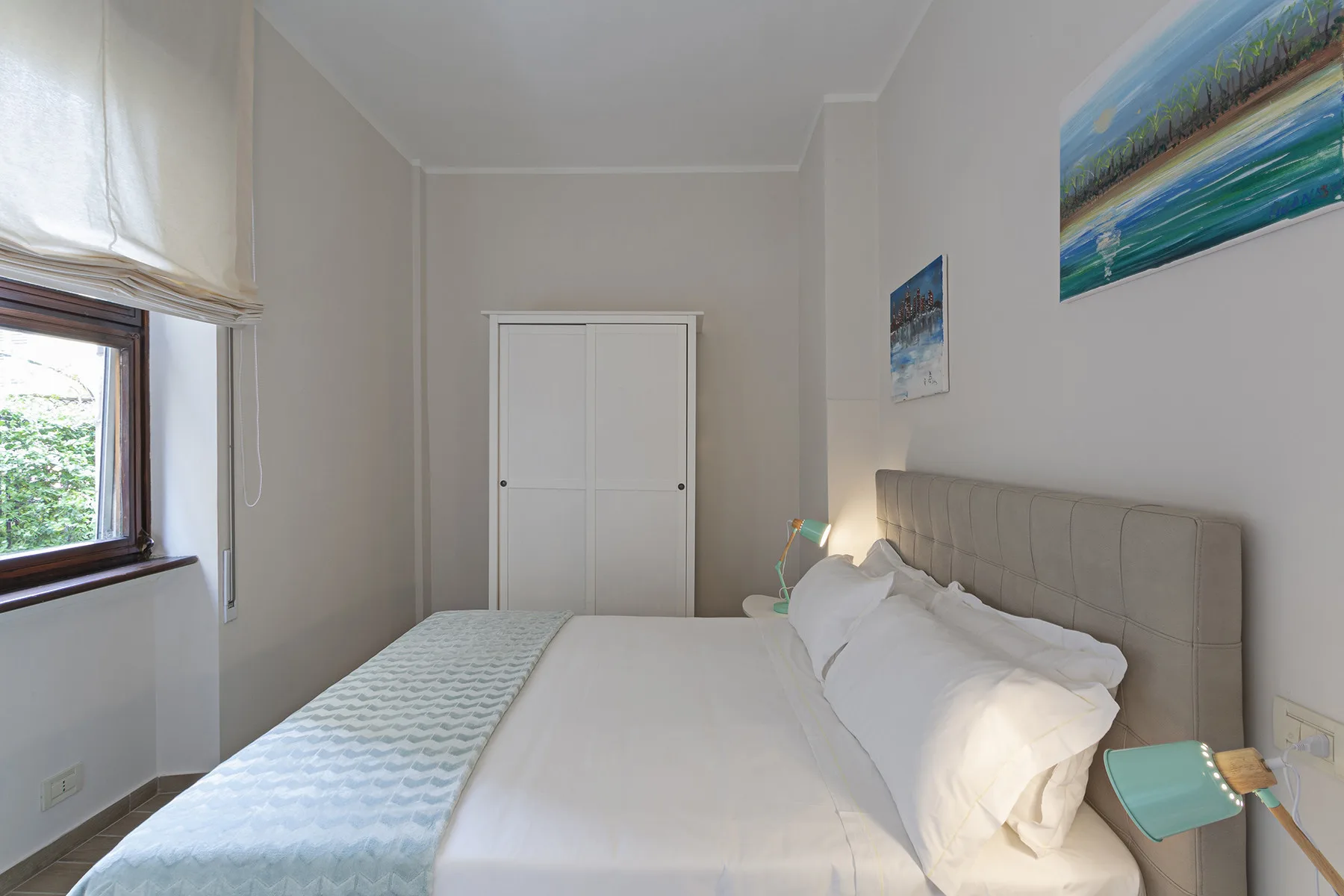 A bedroom with a neatly made bed and a window.