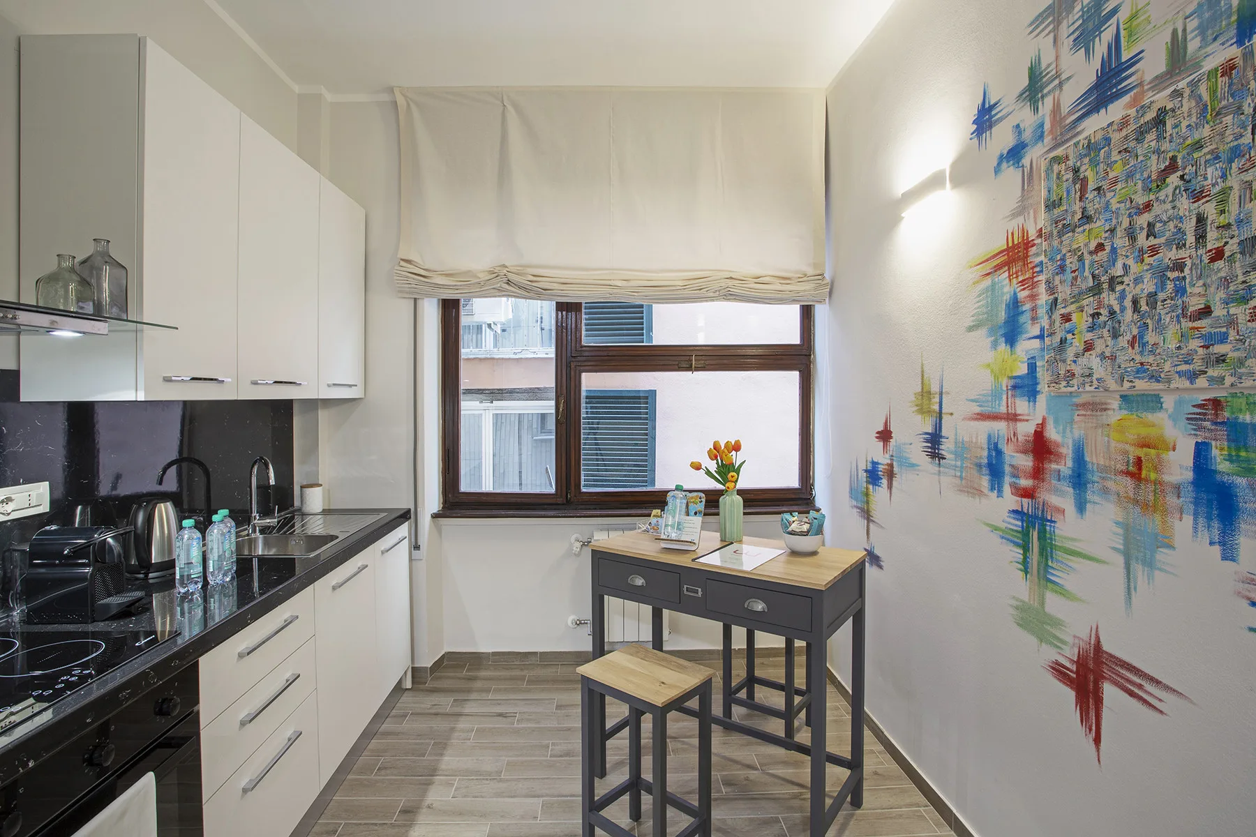 A kitchen with white cabinets, a dark countertop, and a small dining table.
