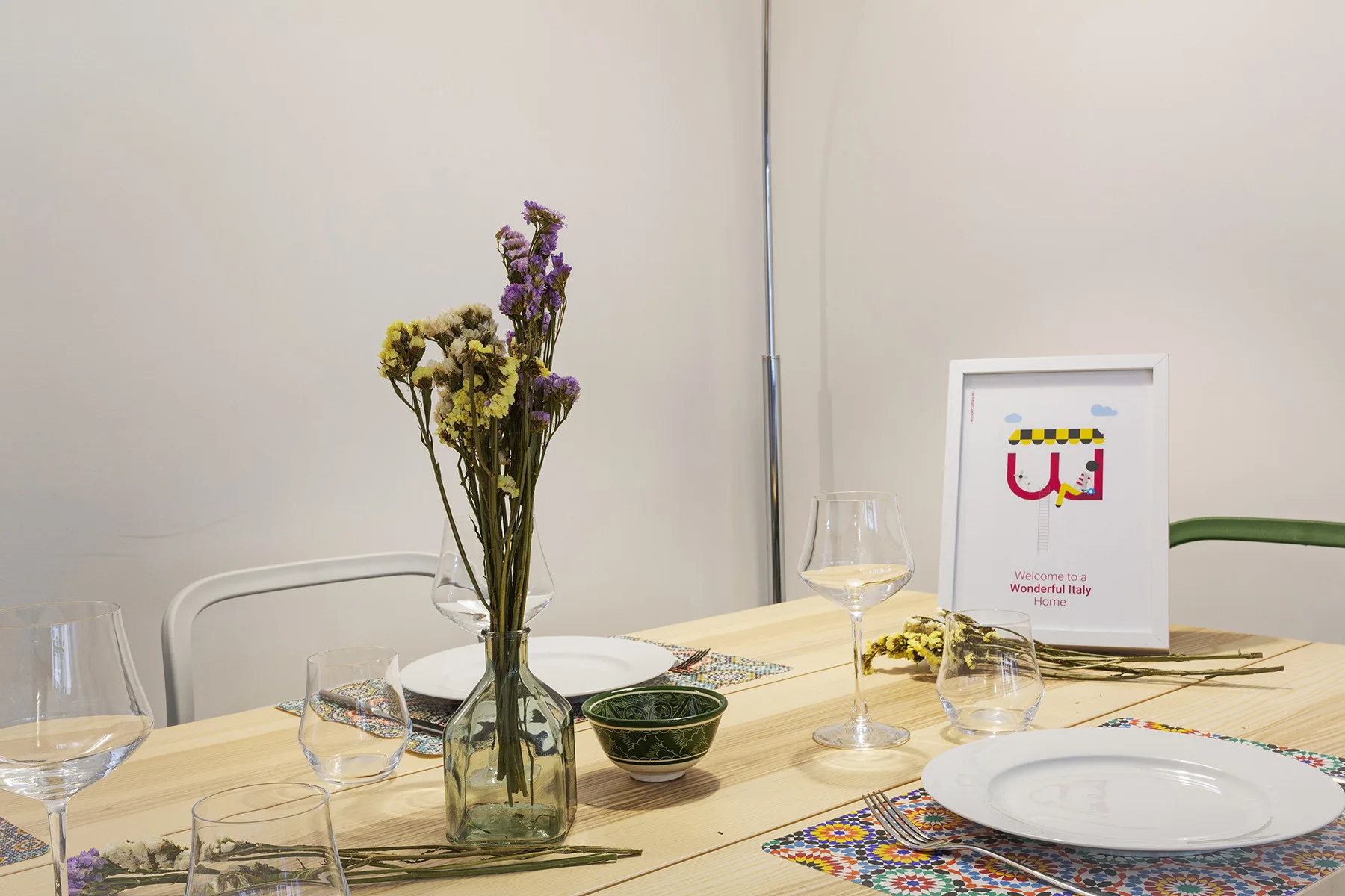 A dining table is set with plates, glasses, and a vase of flowers.