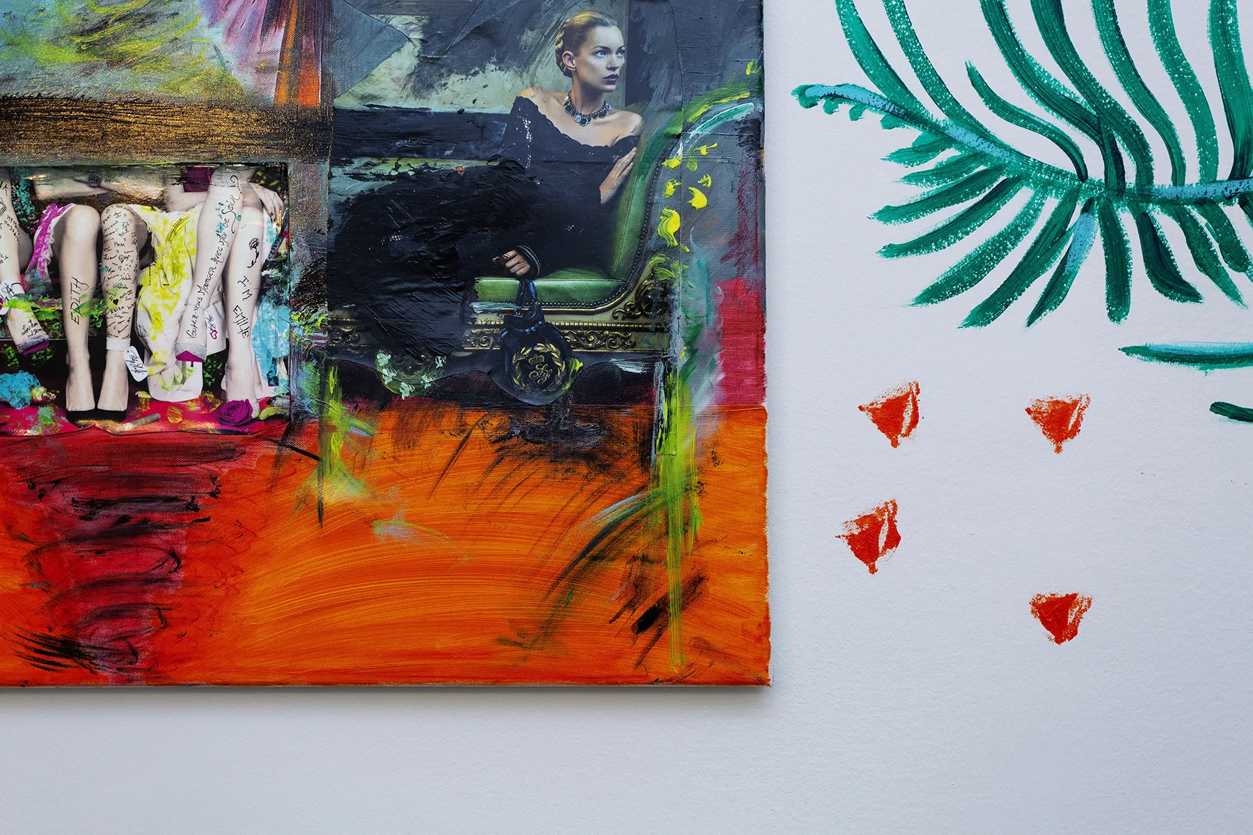 A colorful abstract painting hangs beside a green leaf motif on a light wall.