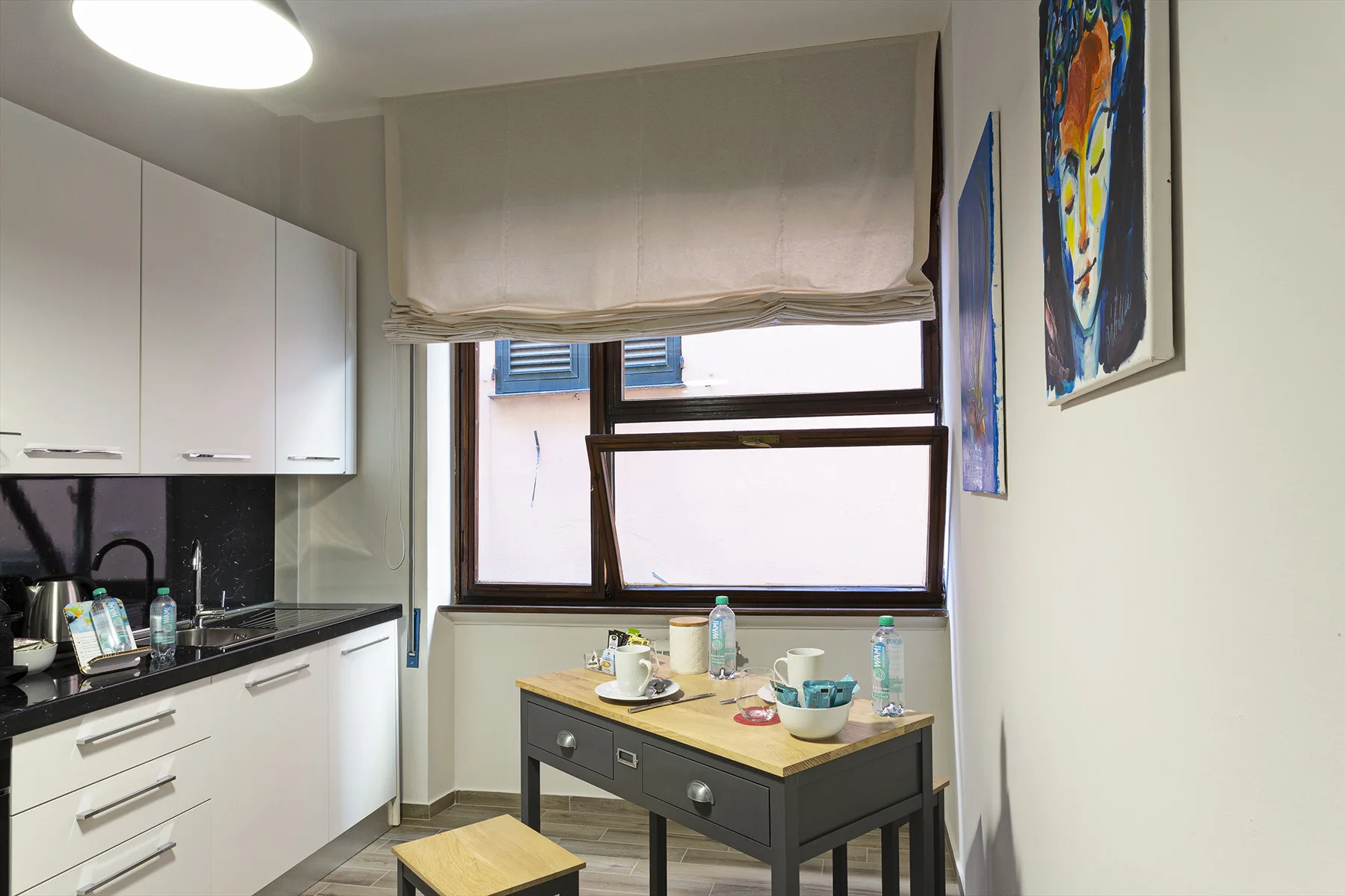 A compact kitchen and dining area with a table beneath a large window.