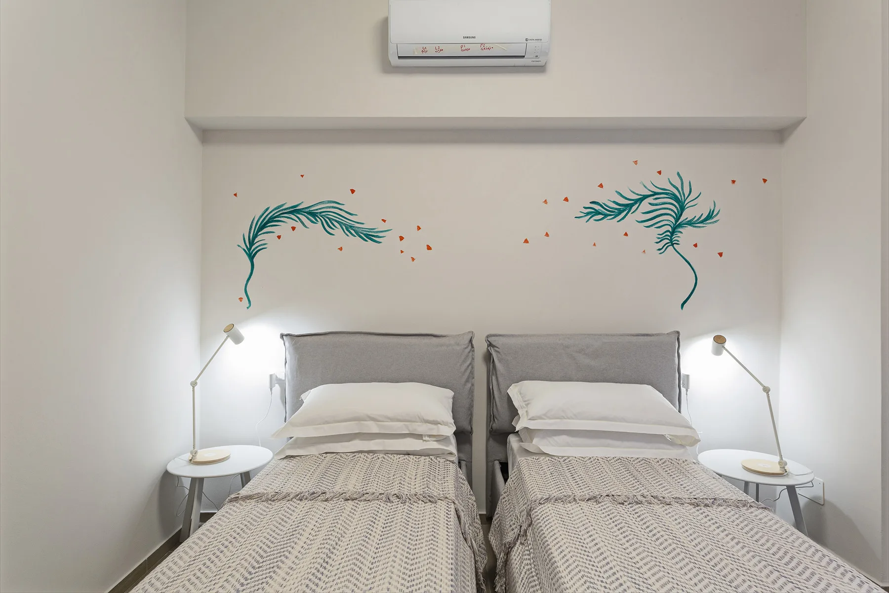 A bedroom with two beds, bedside tables, and decorative wall art.