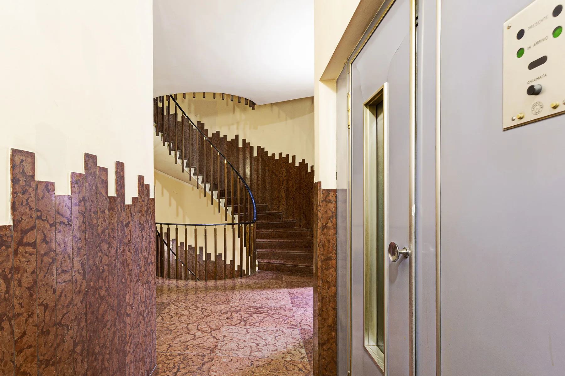 A stairwell with a curved staircase and patterned flooring.