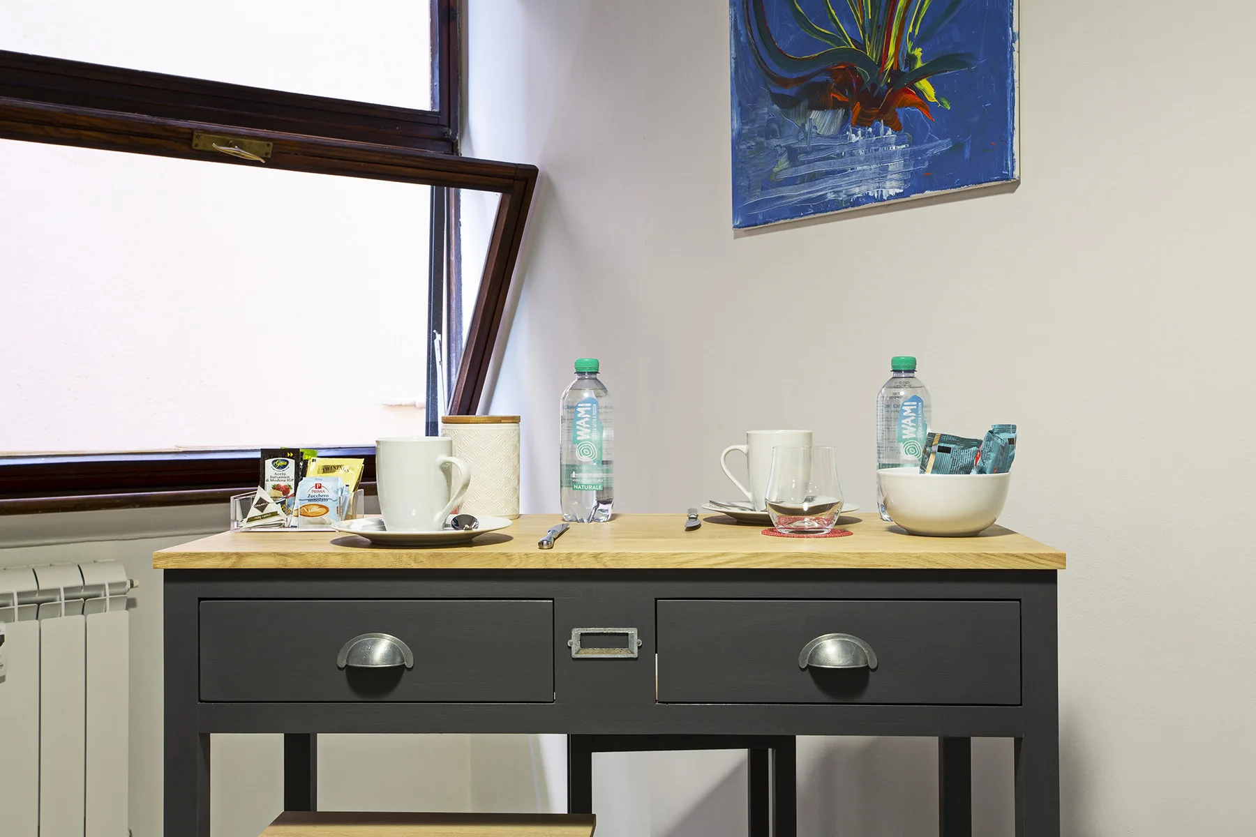 A small table with drinks and cups sits beside an open window.