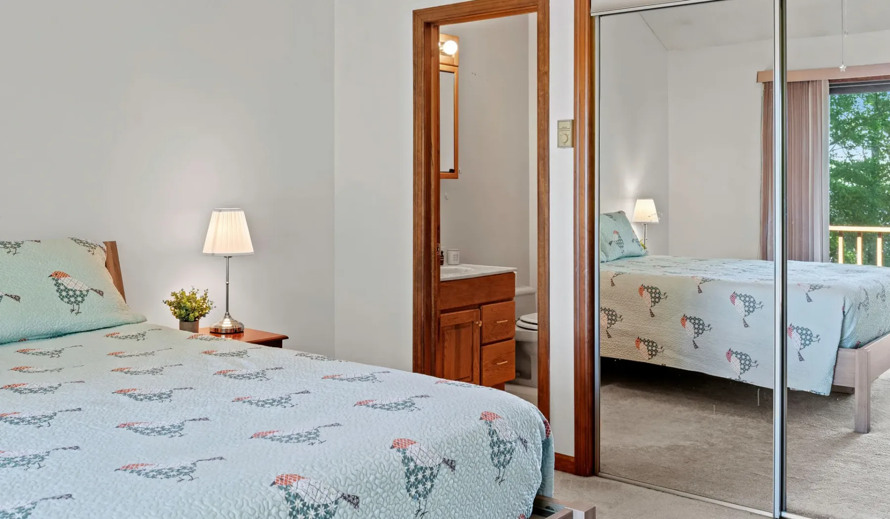 Un dormitorio con ropa de cama estampada y puertas de armario con espejo.
