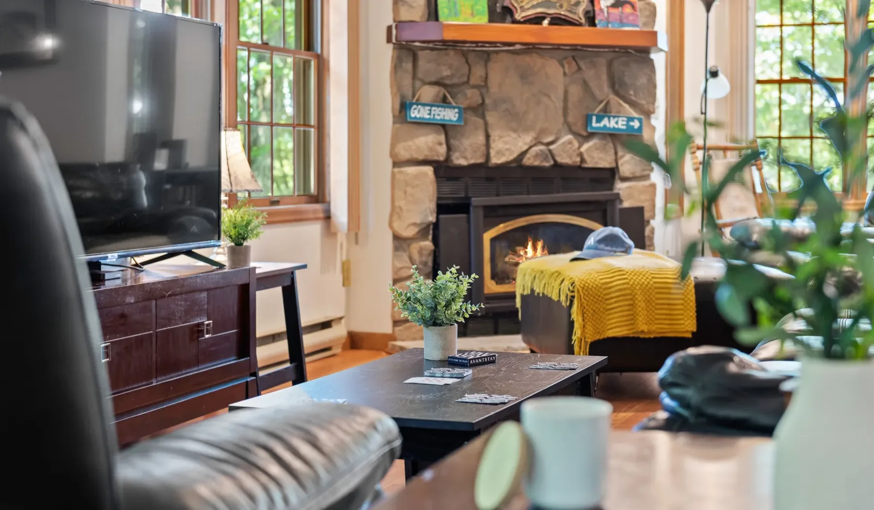 Una sala de estar con chimenea de piedra, televisor y asientos.