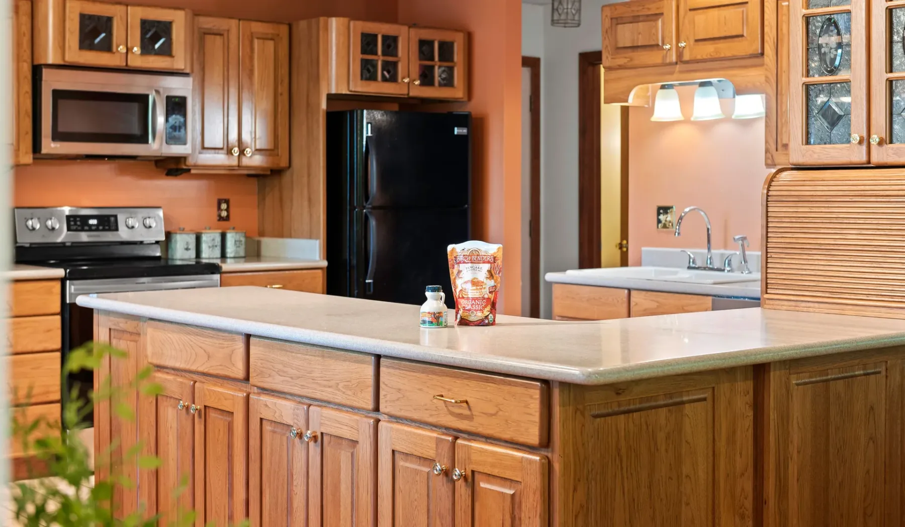Una cocina con gabinetes de madera, una isla central y electrodomésticos de acero inoxidable.