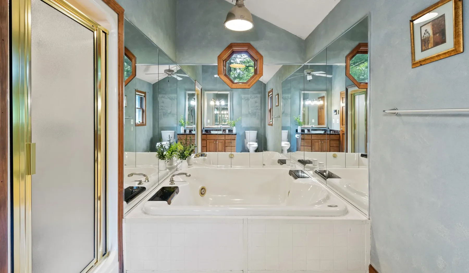 Un baño con una bañera grande frente a una pared de espejos.