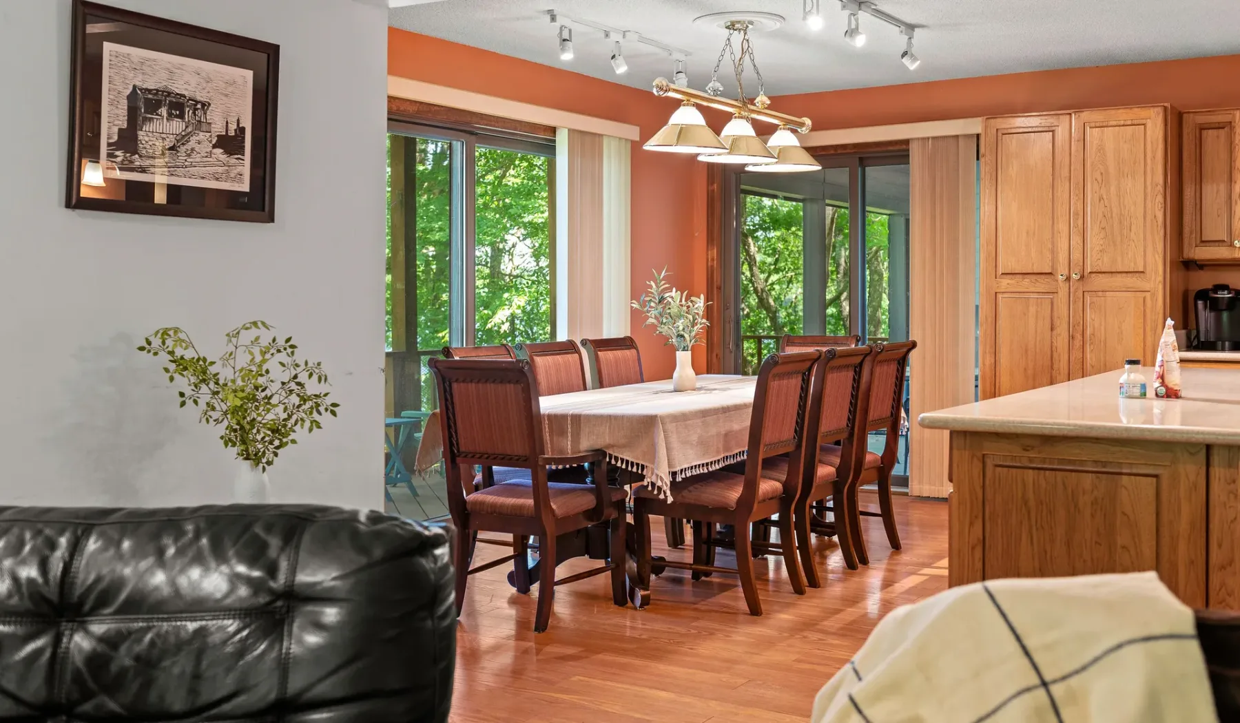 Comedor con una mesa puesta y muebles de madera junto a grandes ventanas.
