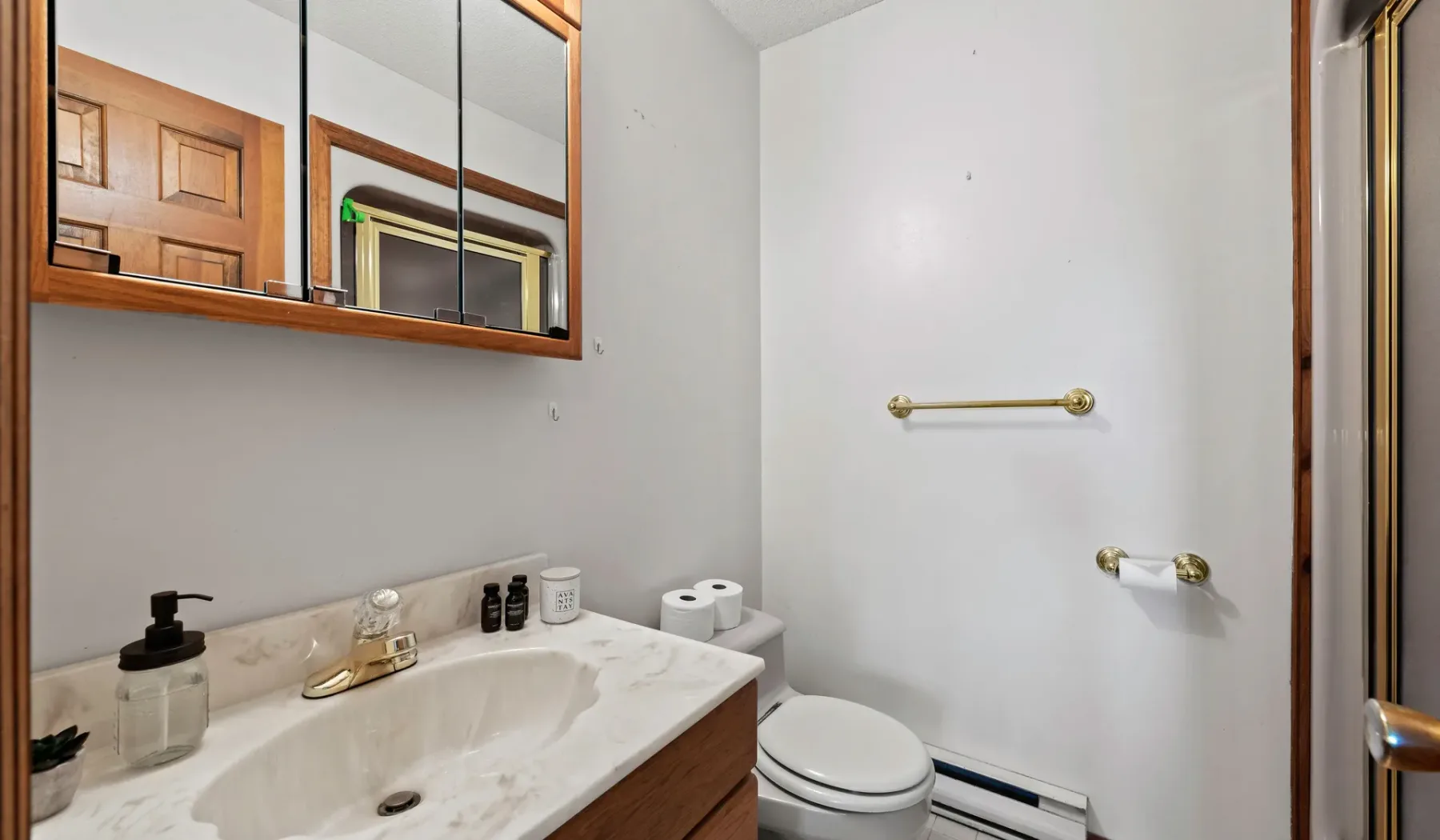 Un baño con lavabo, espejo e inodoro.