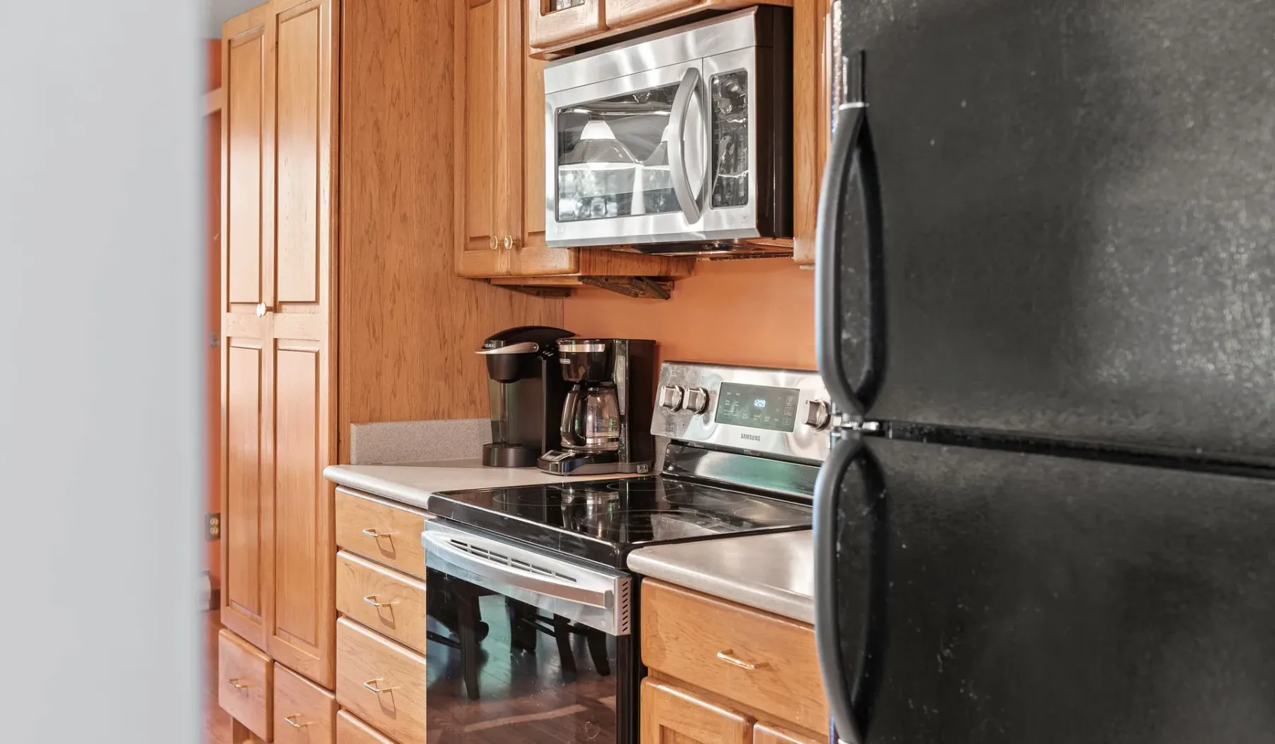 Una cocina con gabinetes de madera, una estufa y un refrigerador.