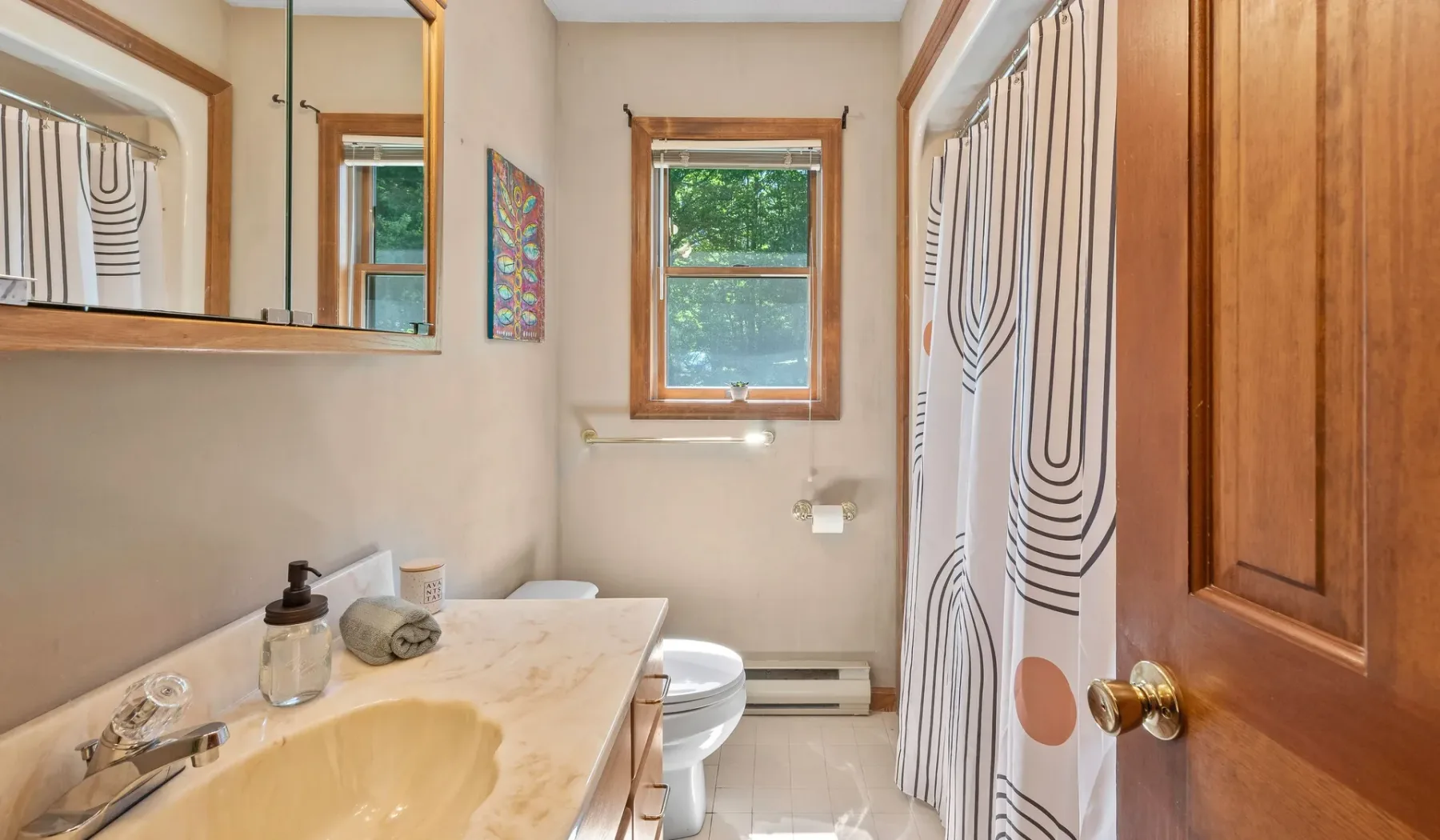 Un baño con lavabo, inodoro y cortina de ducha estampada.