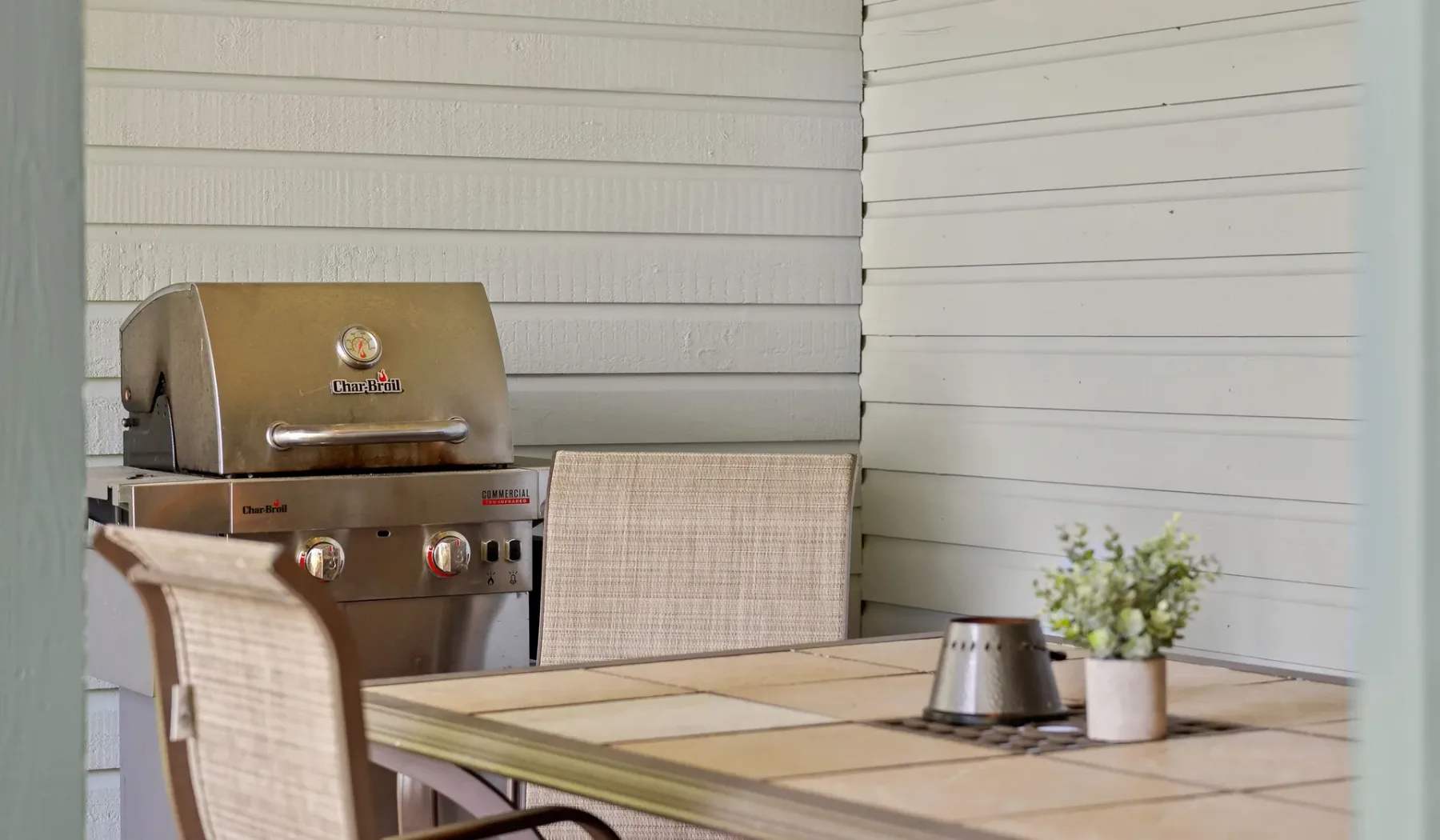 Un comedor al aire libre con una mesa, asientos y una parrilla.