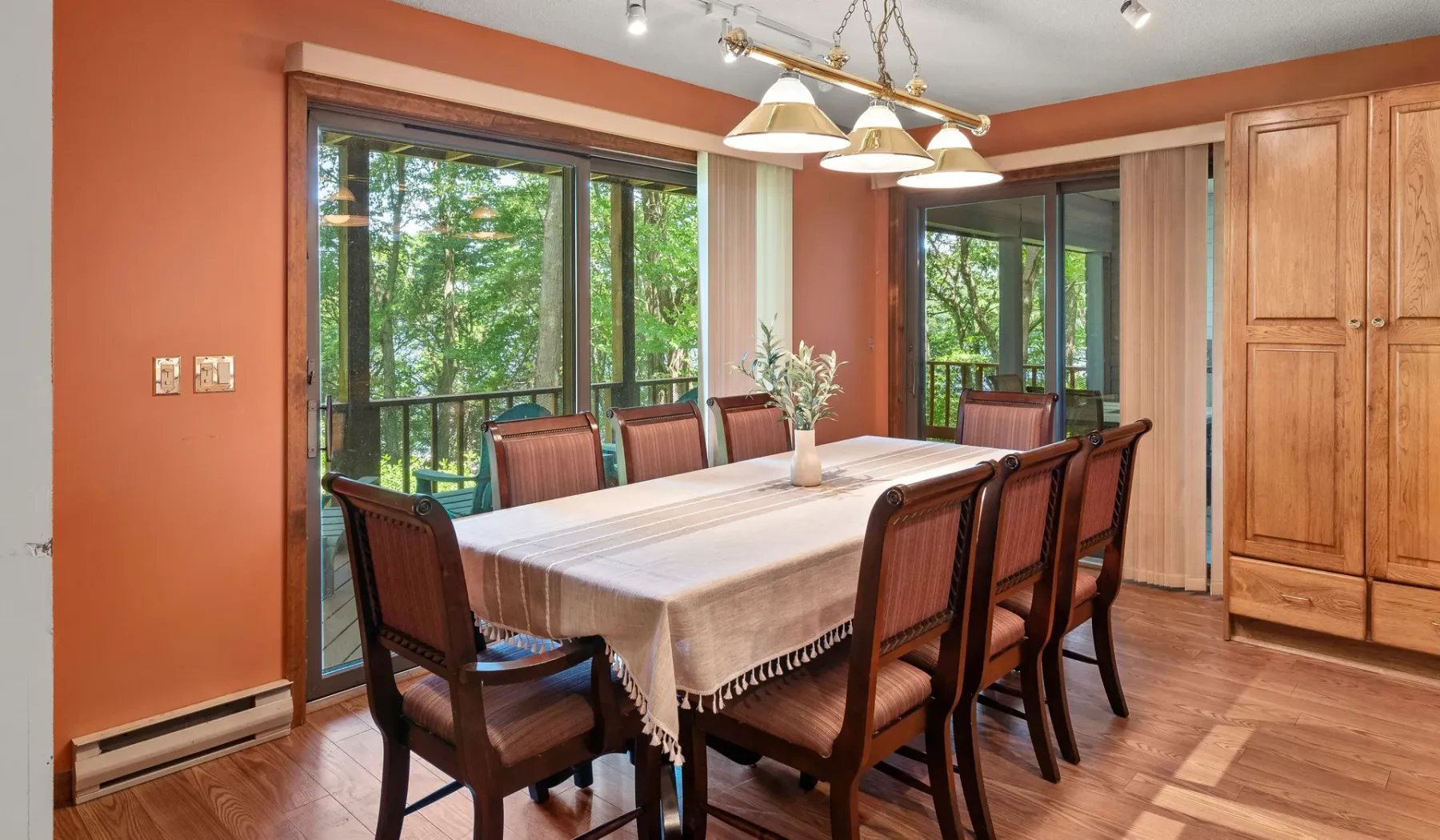 Comedor con una mesa larga y sillas junto a grandes ventanas.