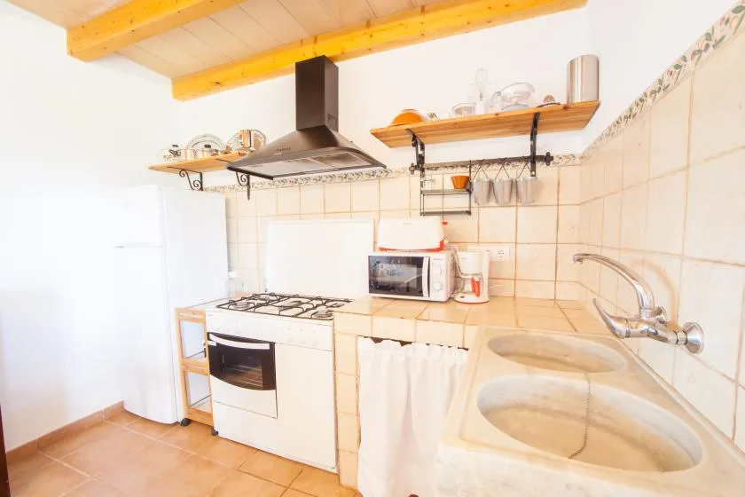 A compact kitchen with a stovetop, microwave, and built-in sink.