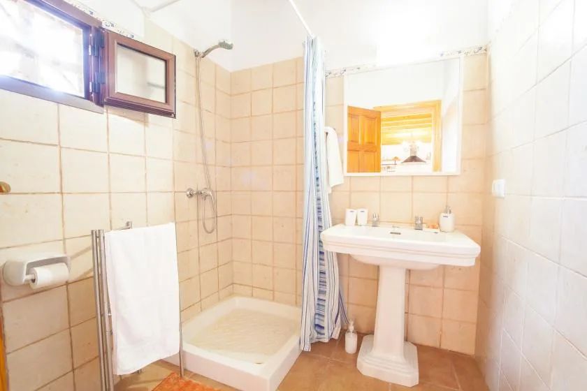A tiled bathroom with a shower, sink, and mirror.