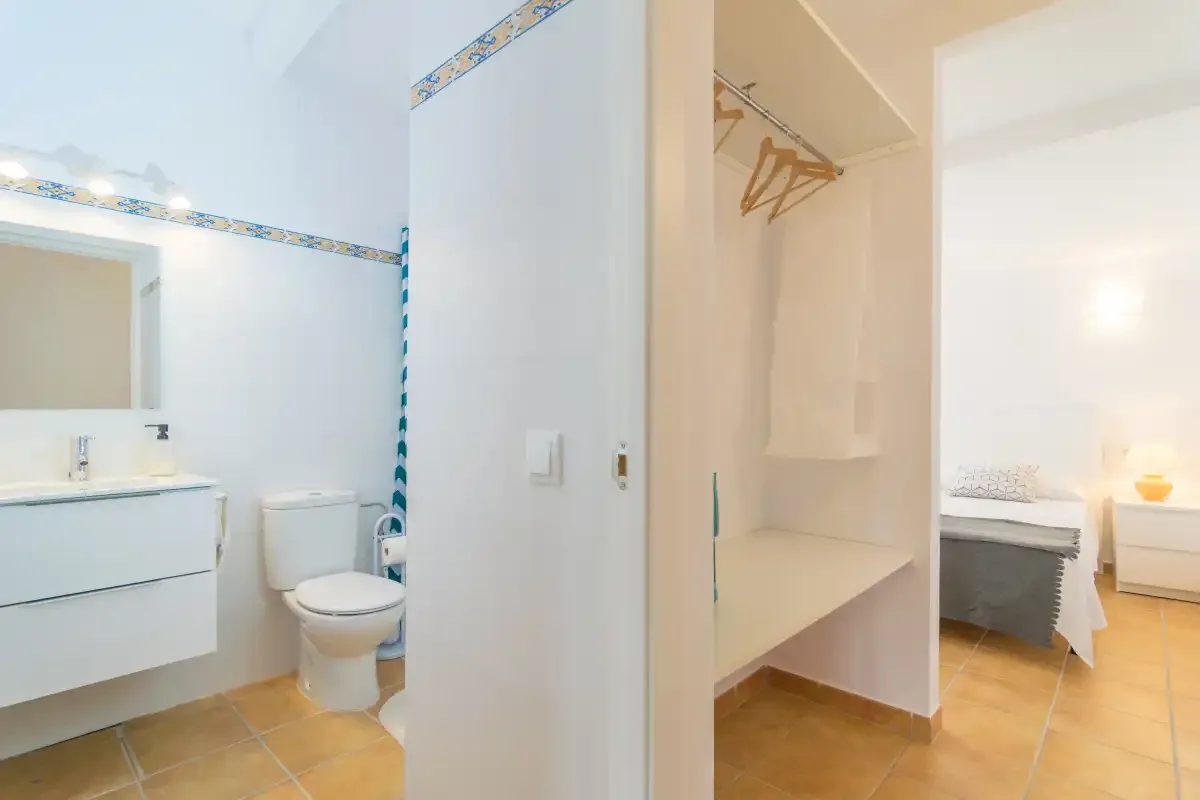 A bathroom and an open closet area with hangers are visible.