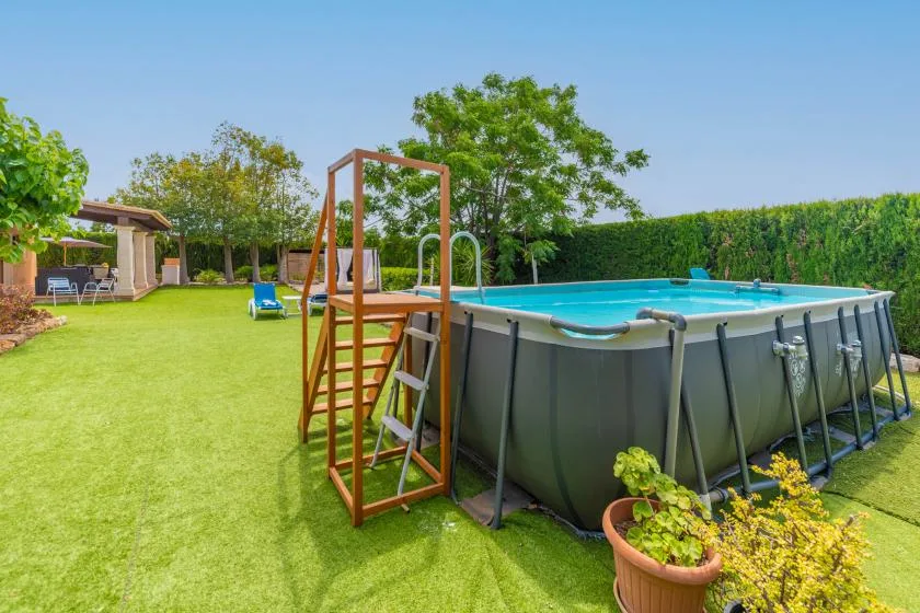 An outdoor swimming pool sits on a lawn beside a wooden ladder.