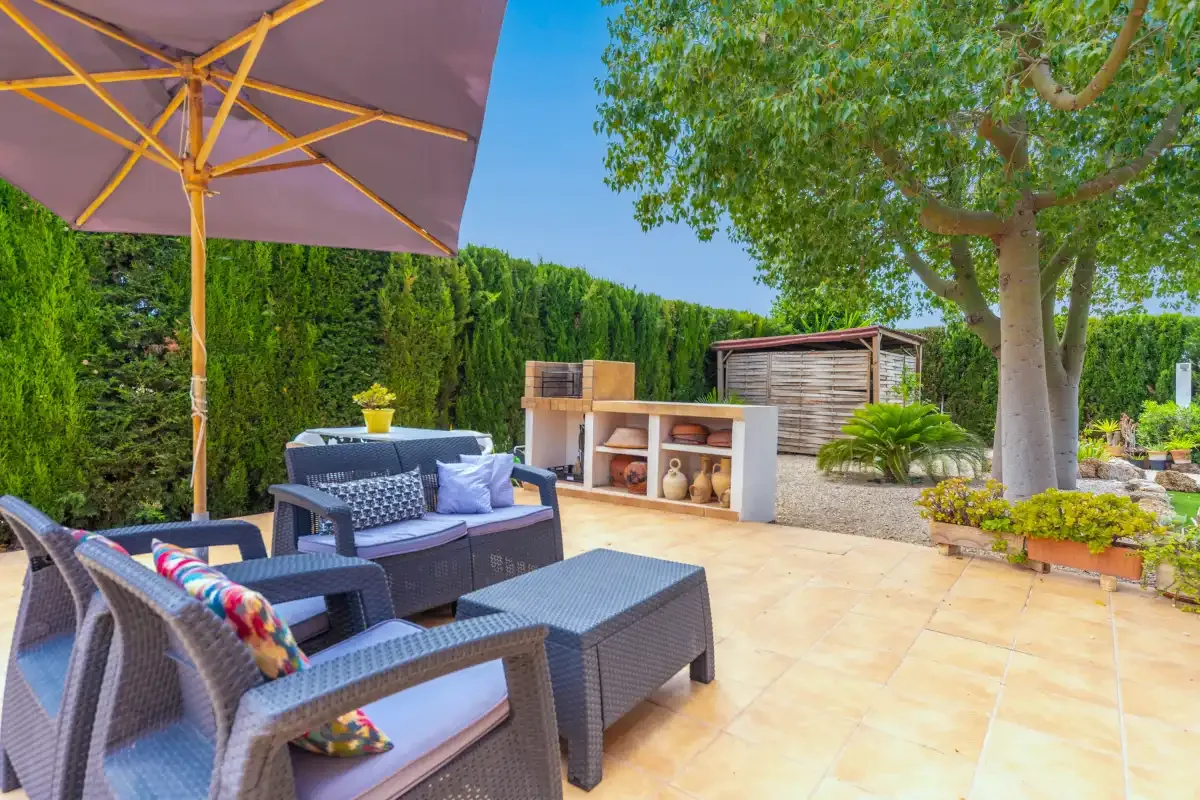 A paved garden patio has outdoor seating beneath a large umbrella.