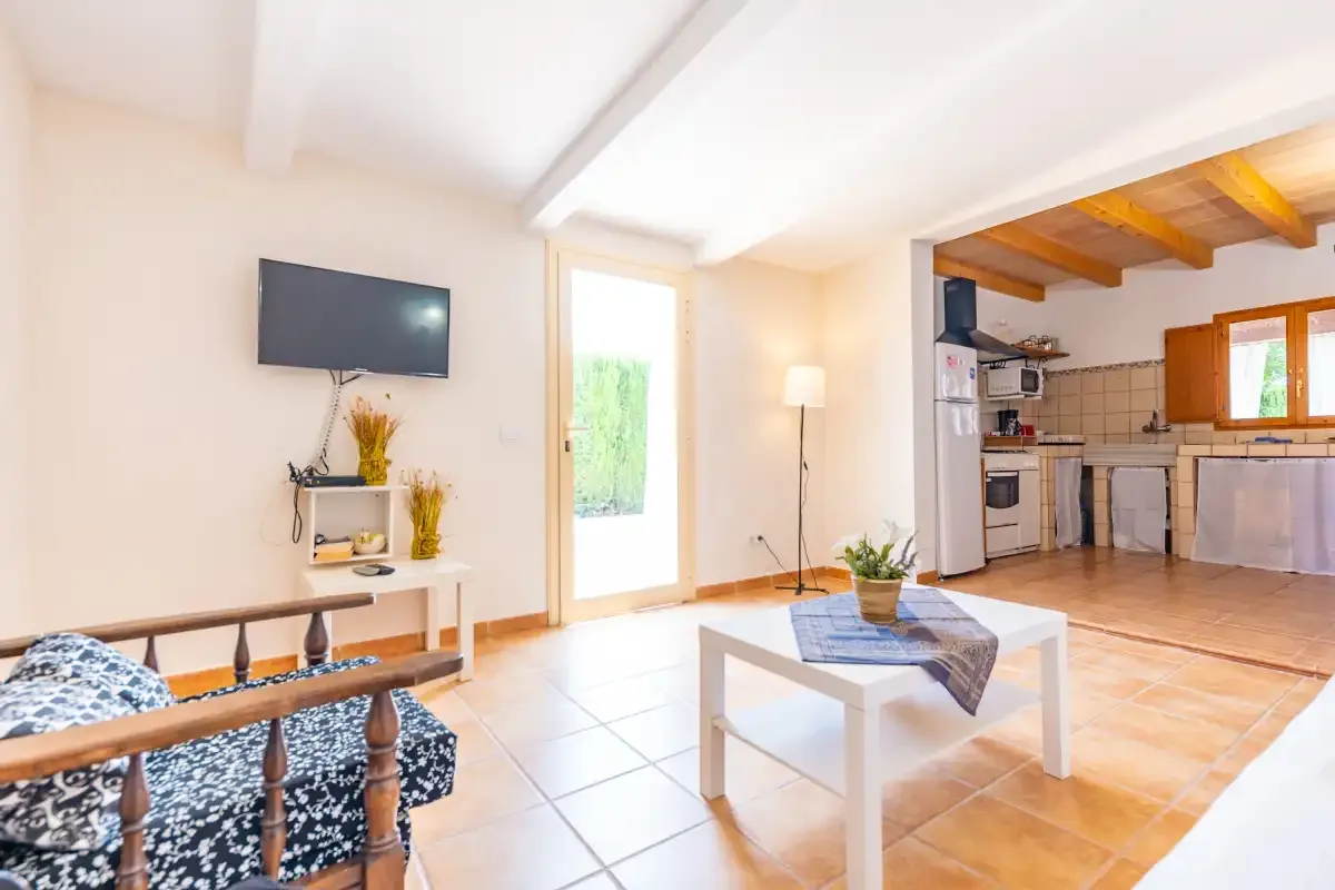 A bright living area opens onto a kitchen, with a television and coffee table.
