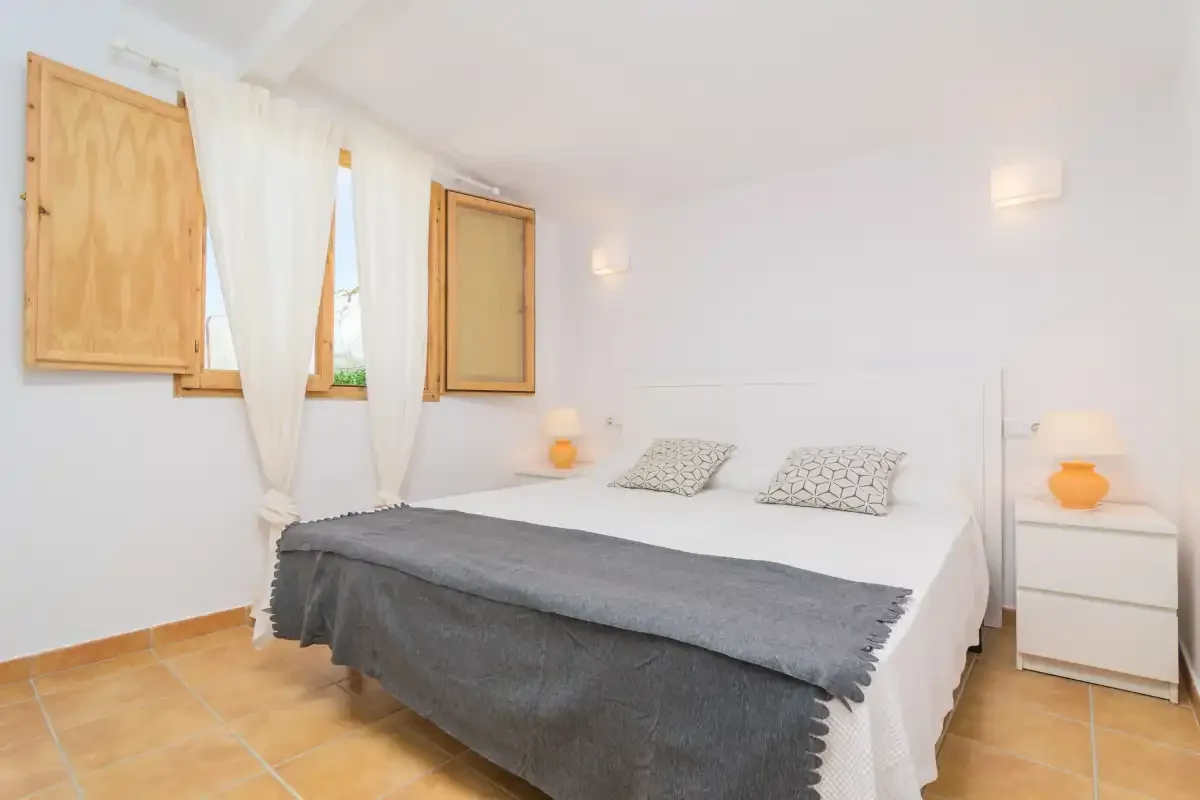 A bedroom with a double bed and white bedside furniture.