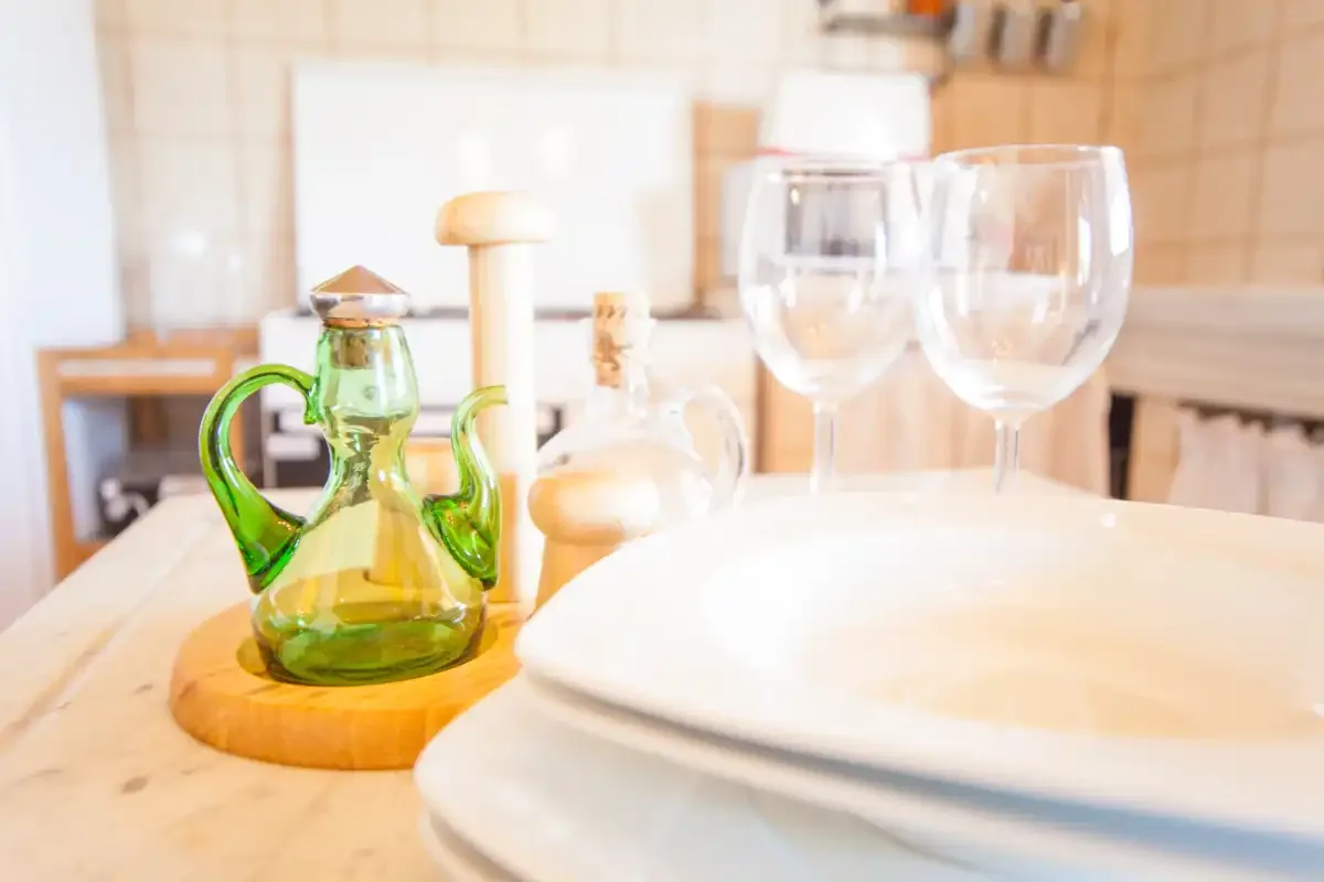 A dining table set with plates, wine glasses, and a green glass cruet.
