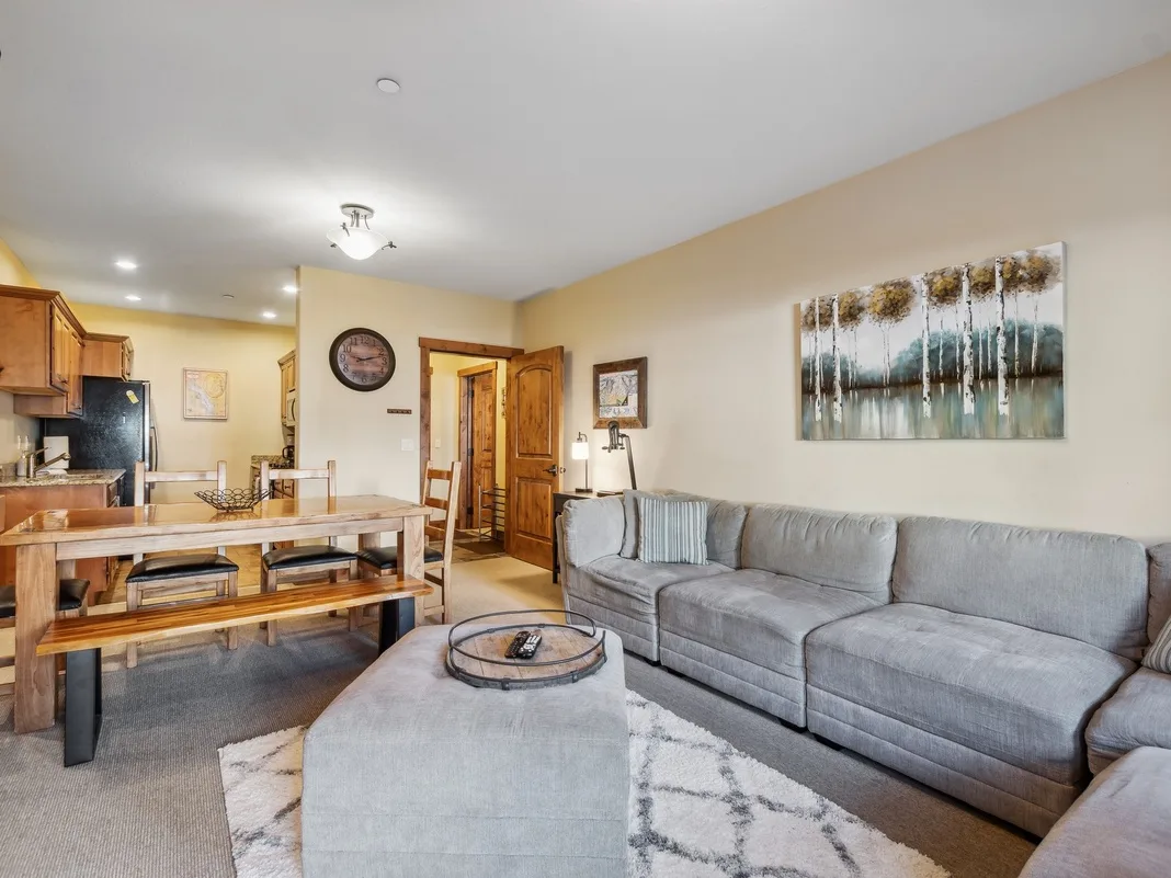 A living room with gray seating and an open dining area.