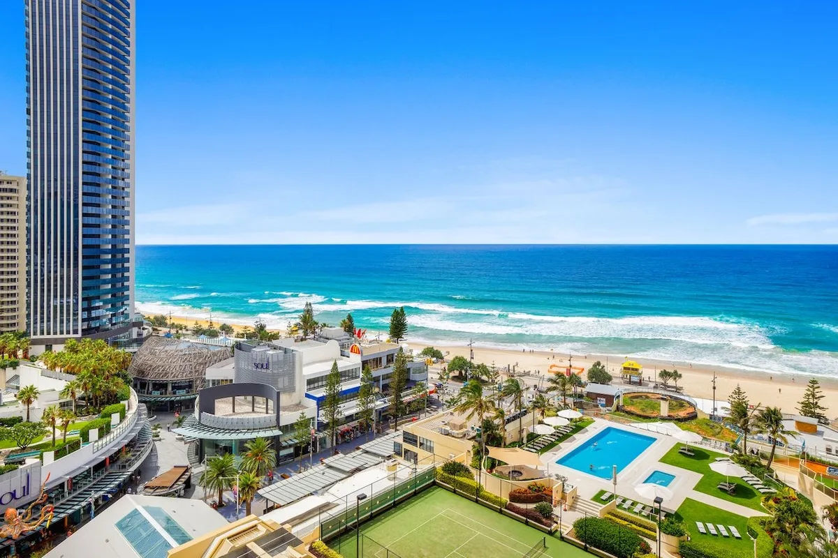 A beachfront resort complex with a pool, tennis court, and ocean views.