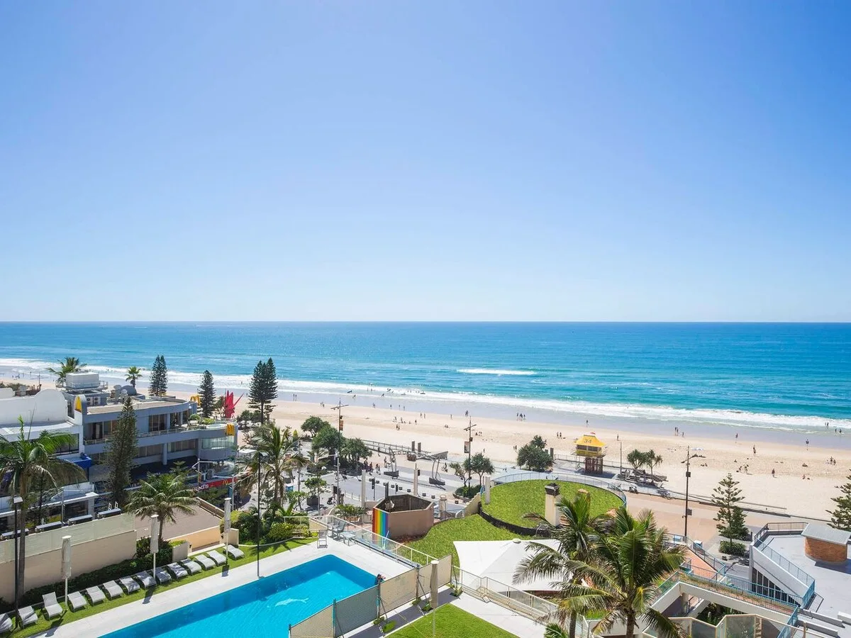 Aerial view of a beach and ocean with a swimming pool in the foreground.