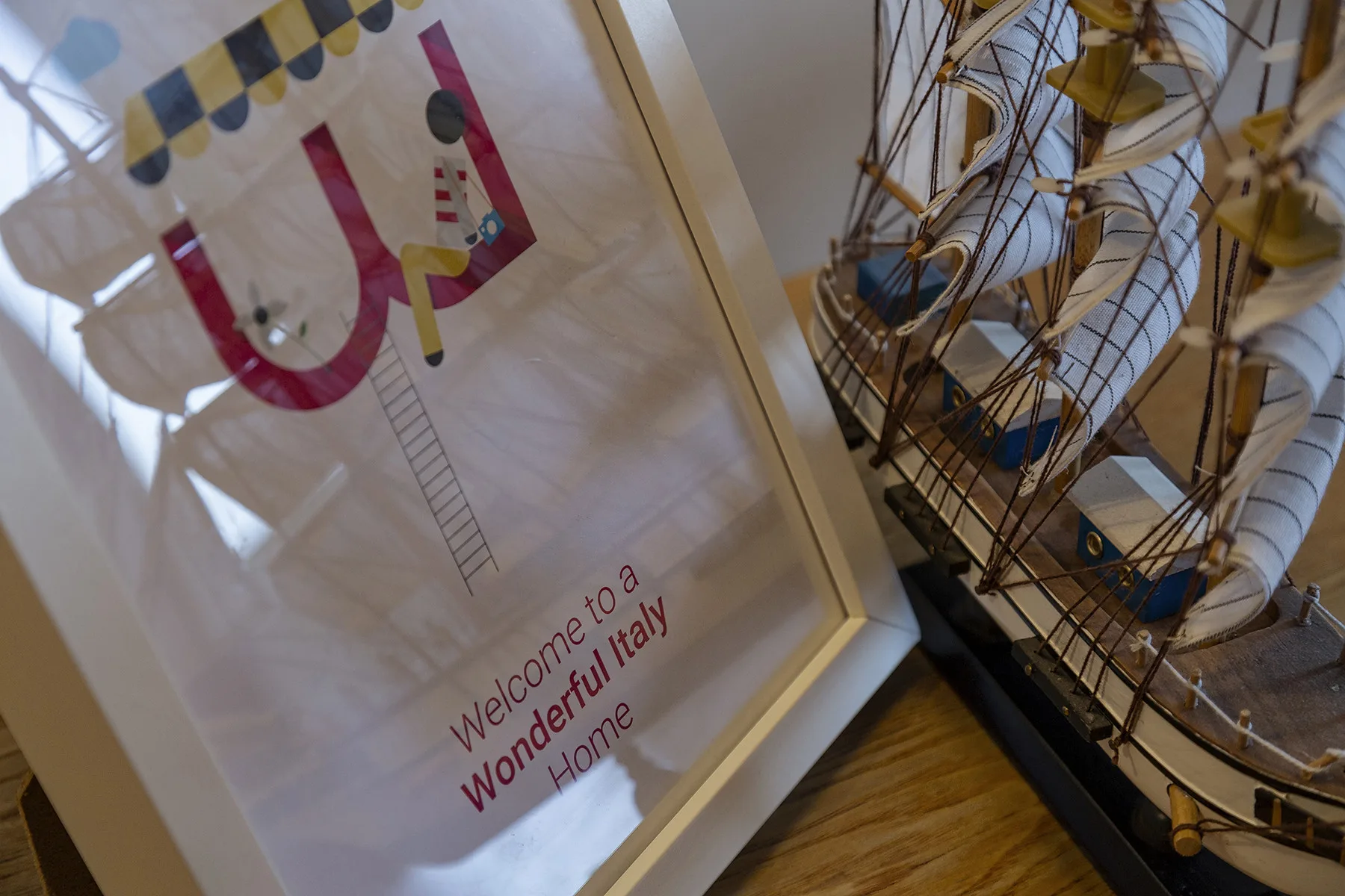 Un cartel de viaje enmarcado y un barco de vela en miniatura se exhiben en el interior.