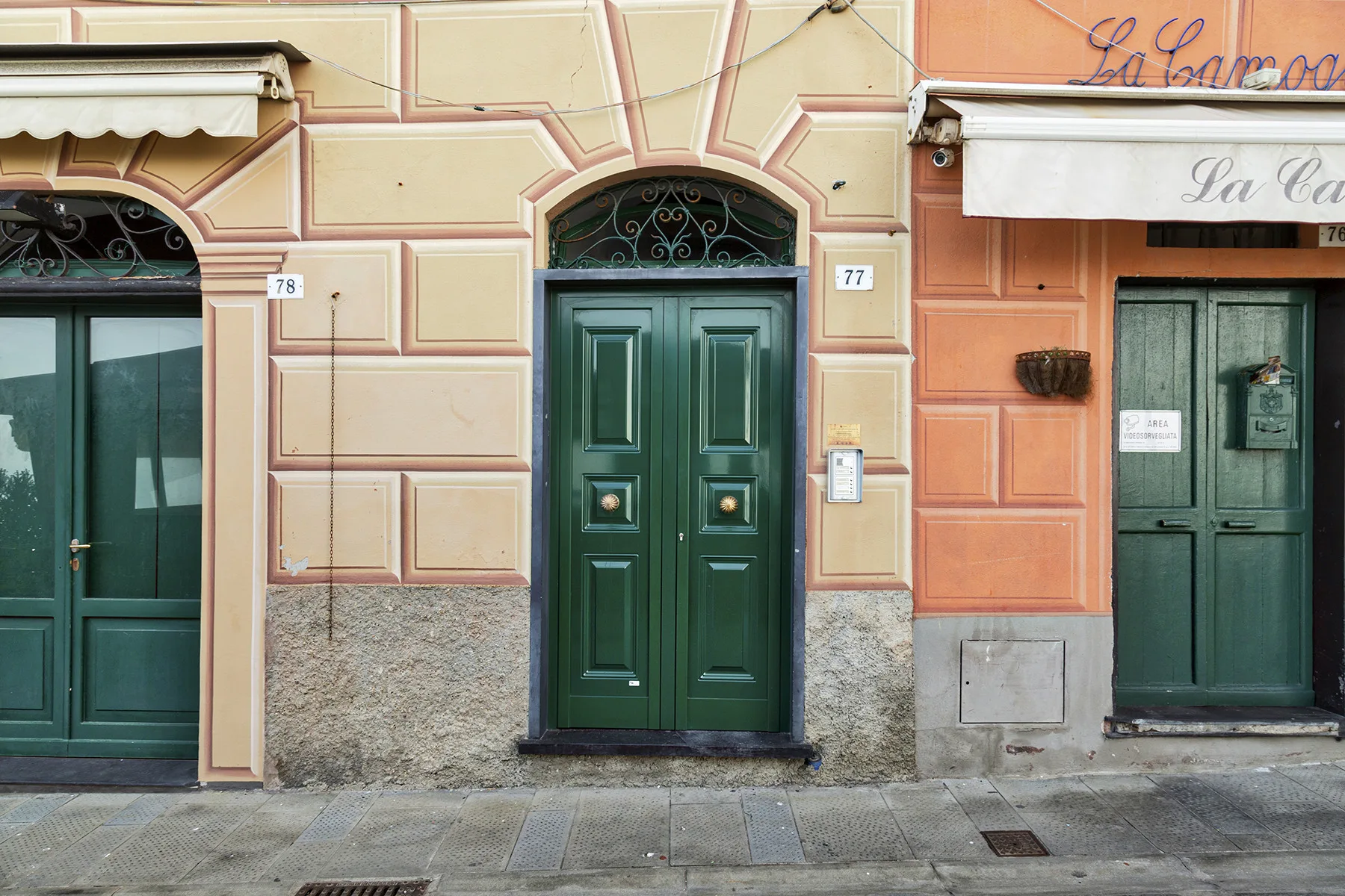 Entradas de edificios a la calle con puertas verde oscuro en fachadas coloridas.