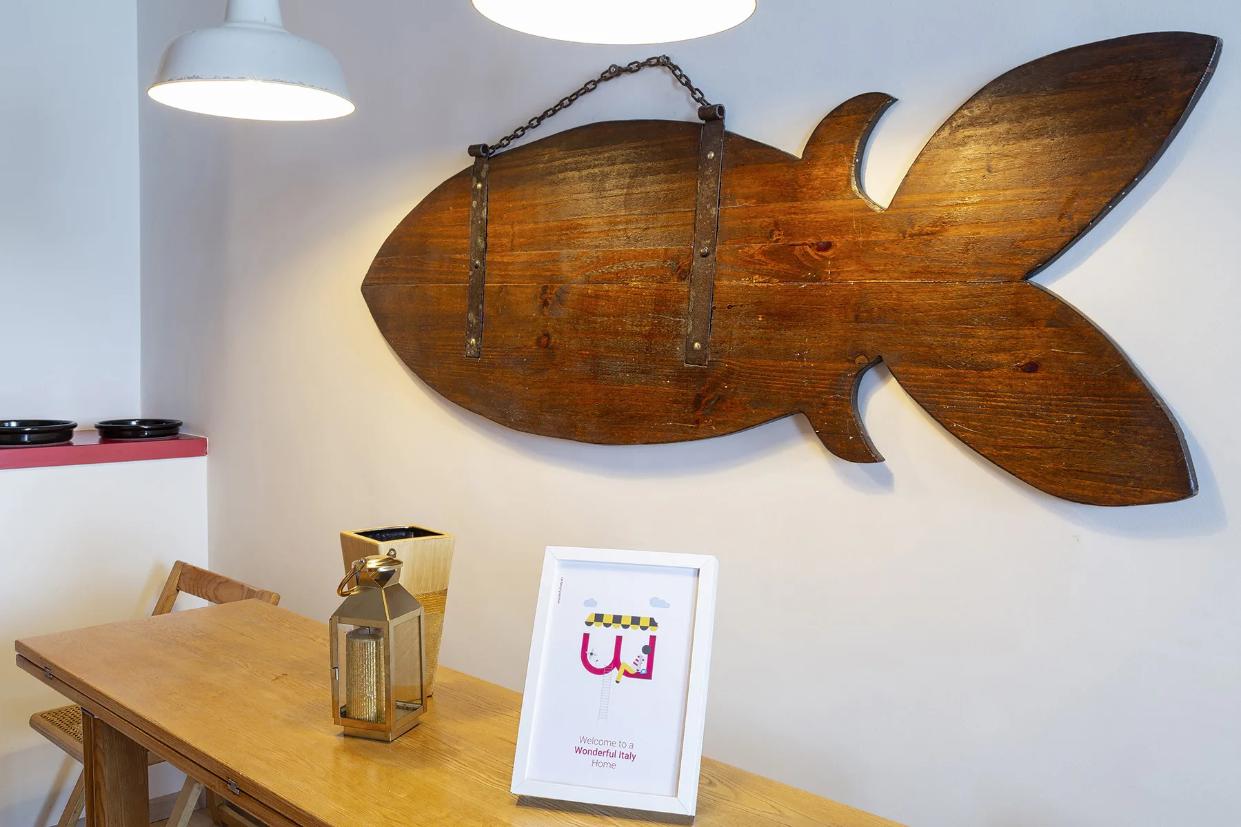 Un comedor con una mesa de madera bajo una gran decoración de pared con forma de pez.