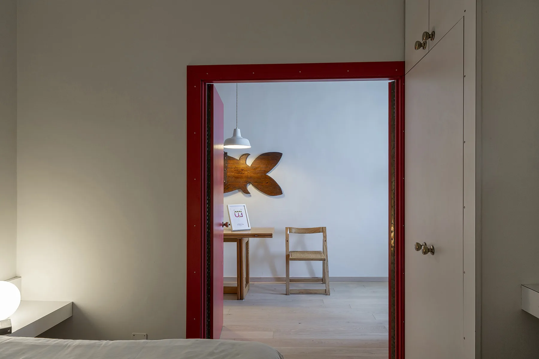 La puerta de un dormitorio enmarca una mesa pequeña y una silla en la habitación contigua.
