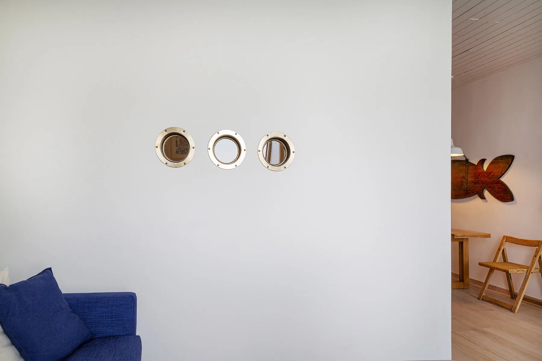 Una zona de estar con asientos azules y adornos redondos en la pared junto a una mesa de madera.