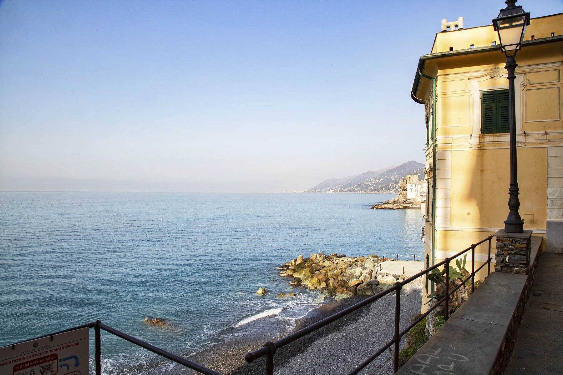 Un paseo junto al mar mira hacia el agua, al lado de un edificio amarillo.