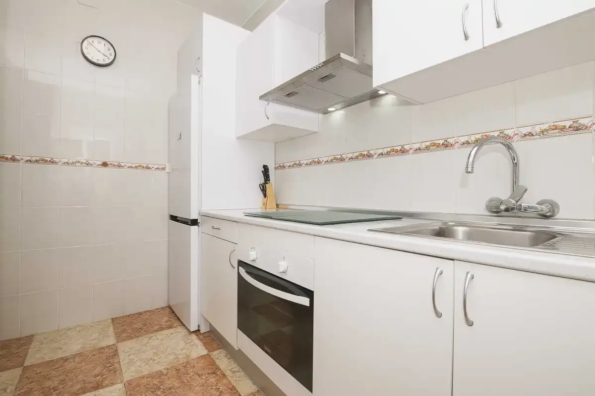 A bright kitchen with white cabinets, a countertop, and a sink.