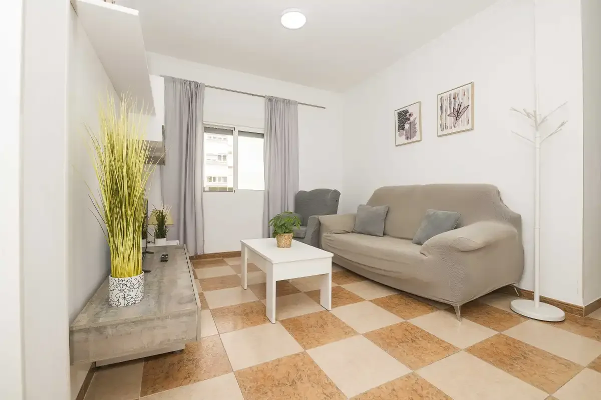 A bright living room with seating, a coffee table, and patterned tile flooring.