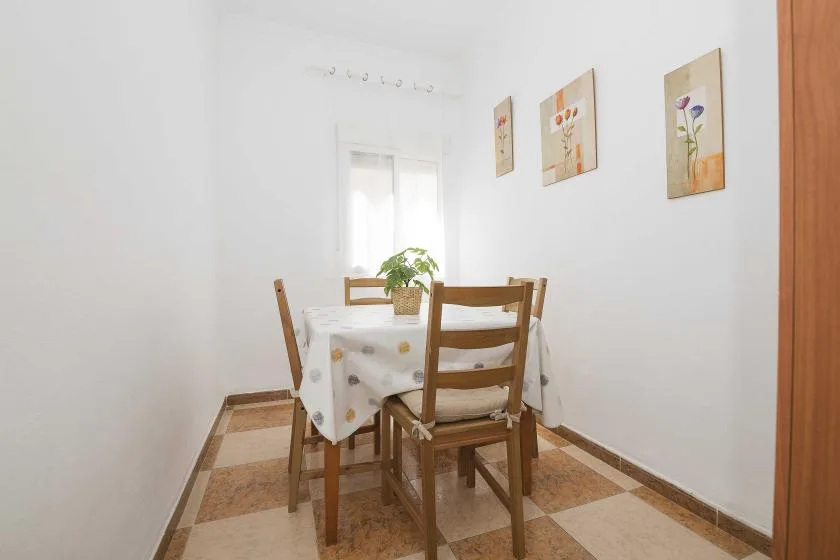 A small dining area with a wooden table and chairs beneath framed wall art.