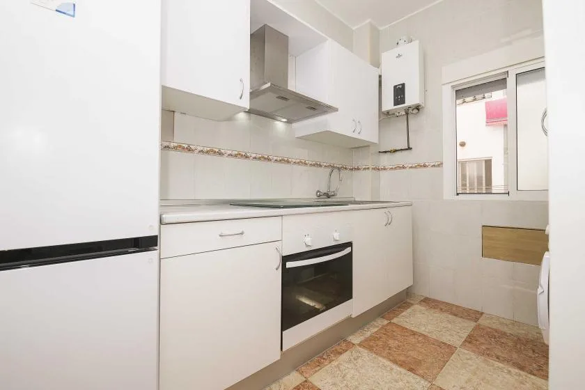 A bright kitchen with white cabinets, a countertop, and a built-in oven.