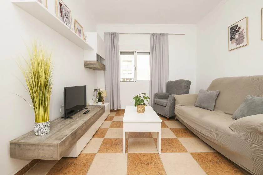 A bright living room with seating, a coffee table, and a television.
