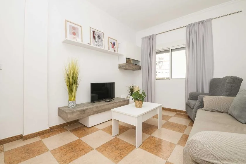A bright living room with seating, a television, and a coffee table.