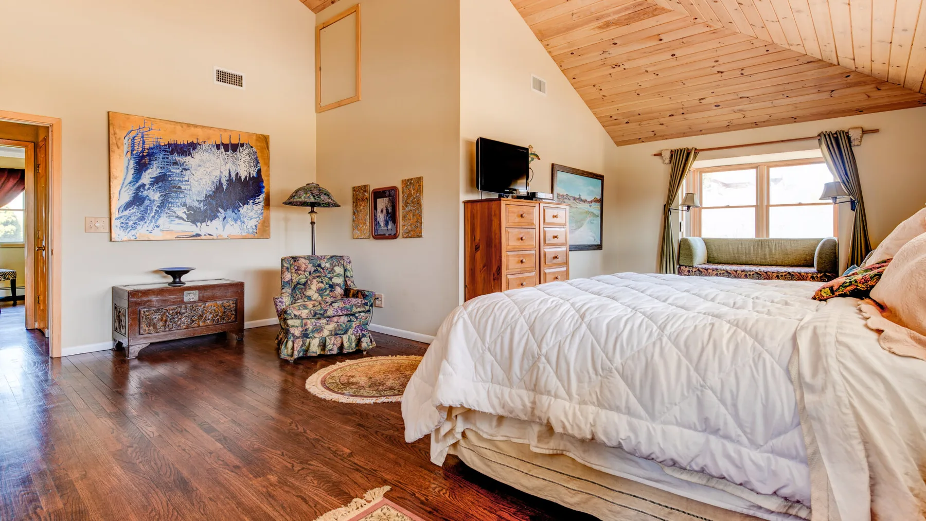 Un dormitorio con una cama, techo de madera y ventana.