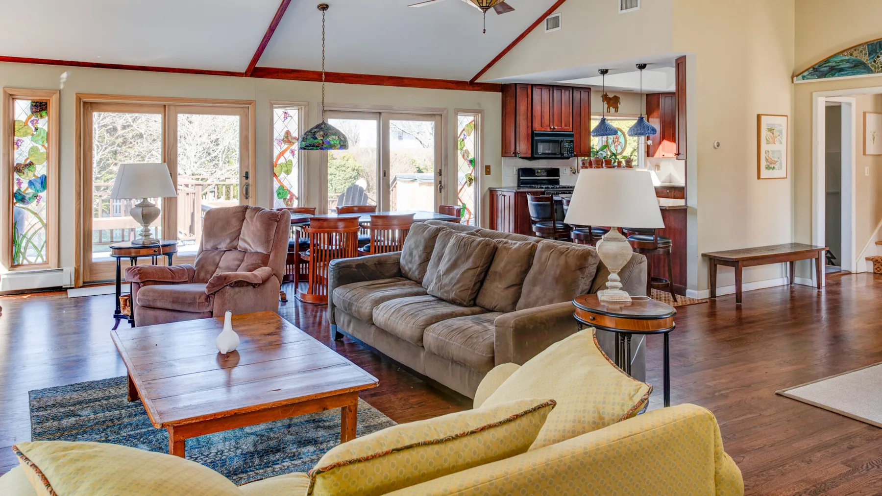 A living room opens into a dining area and kitchen, with seating around a coffee table.