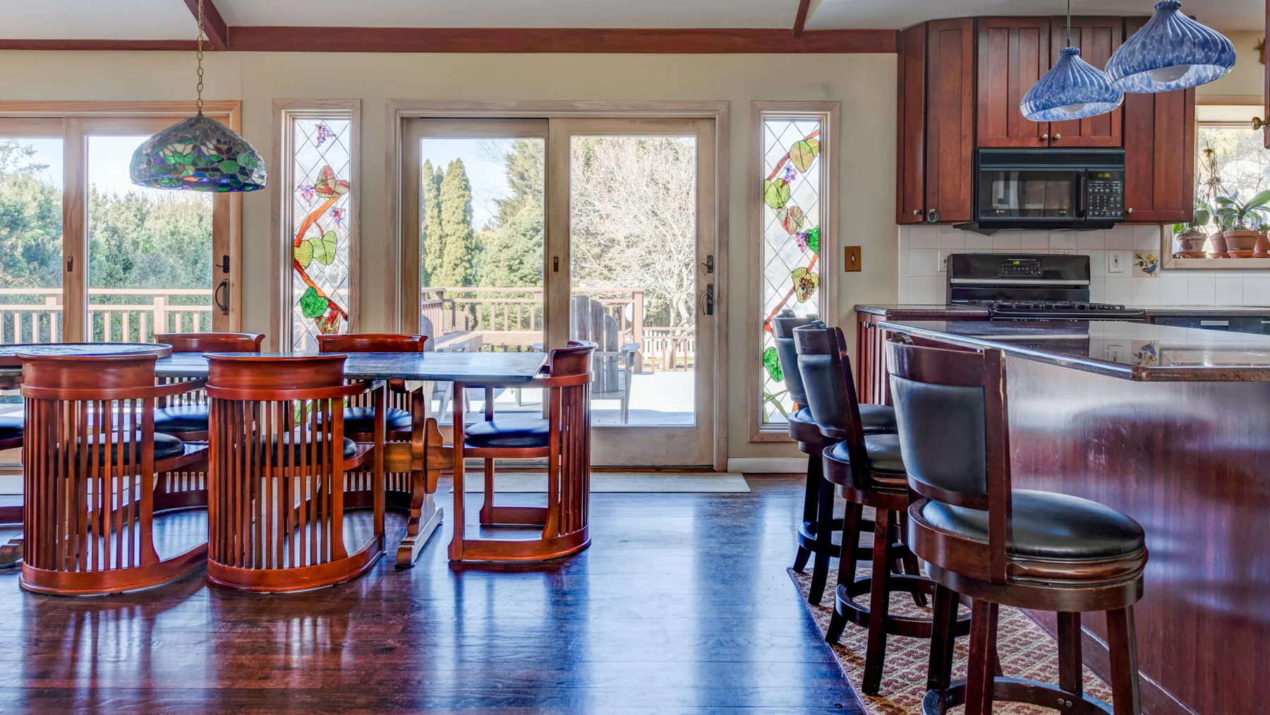 Comedor con mesas y sillas de madera junto a grandes puertas de vidrio.
