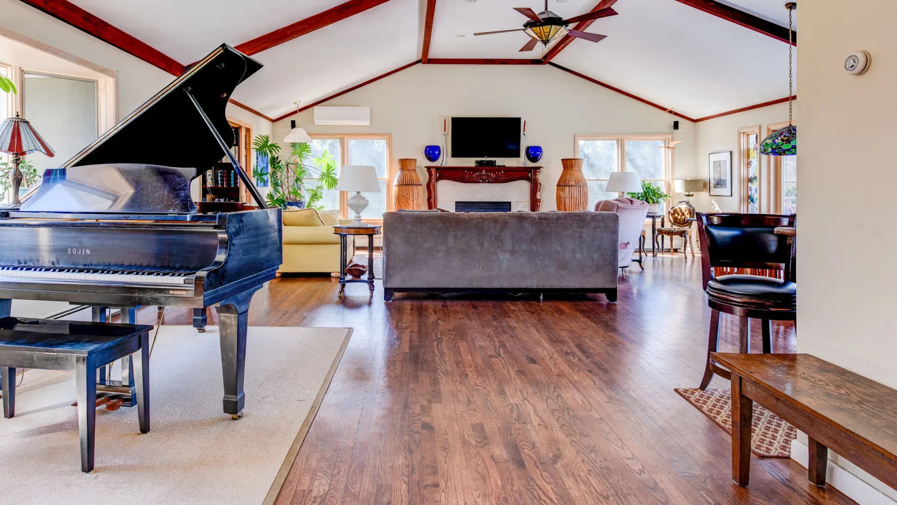 Una amplia sala de estar con un piano de cola, asientos y una chimenea.